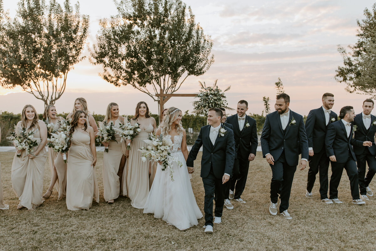bride and groom holding hands with bridal party behind them