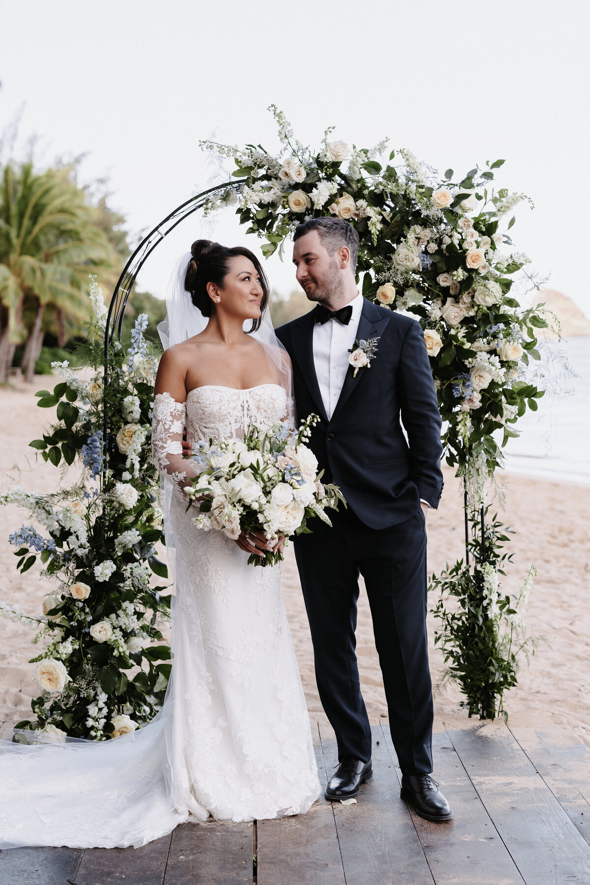 Bride and groom portrait in front of ceremony arch looking at one another
