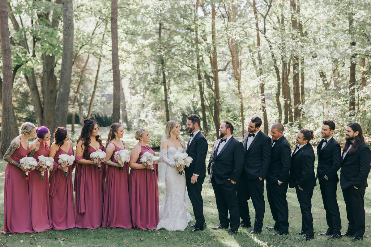 Glamorous wedding party portrait of both bridesmaids in pink and groomsmen in charcoal
