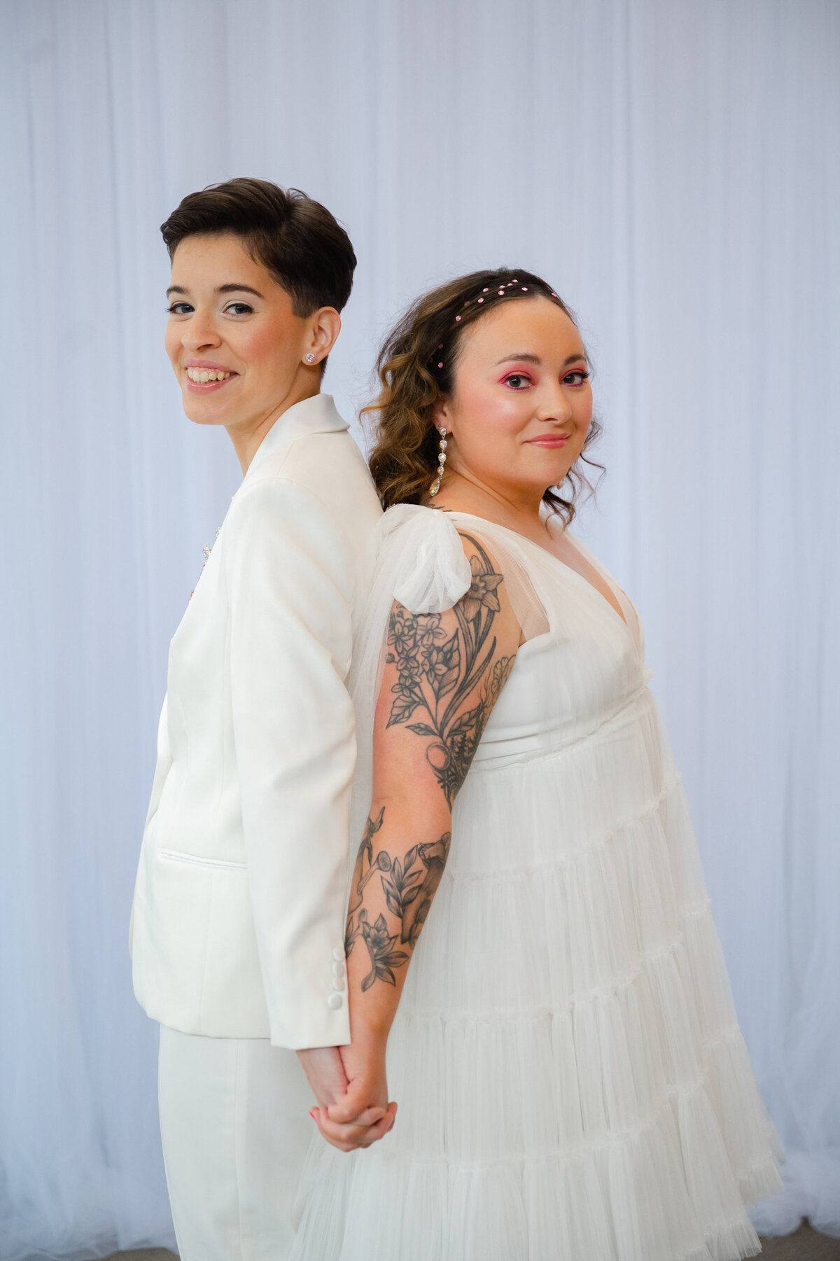Two brides back to back holding hand