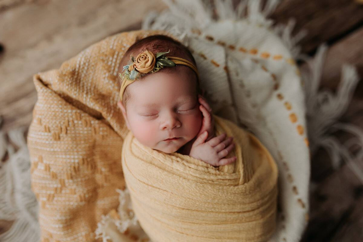 newborn girl wrapped in yellow
