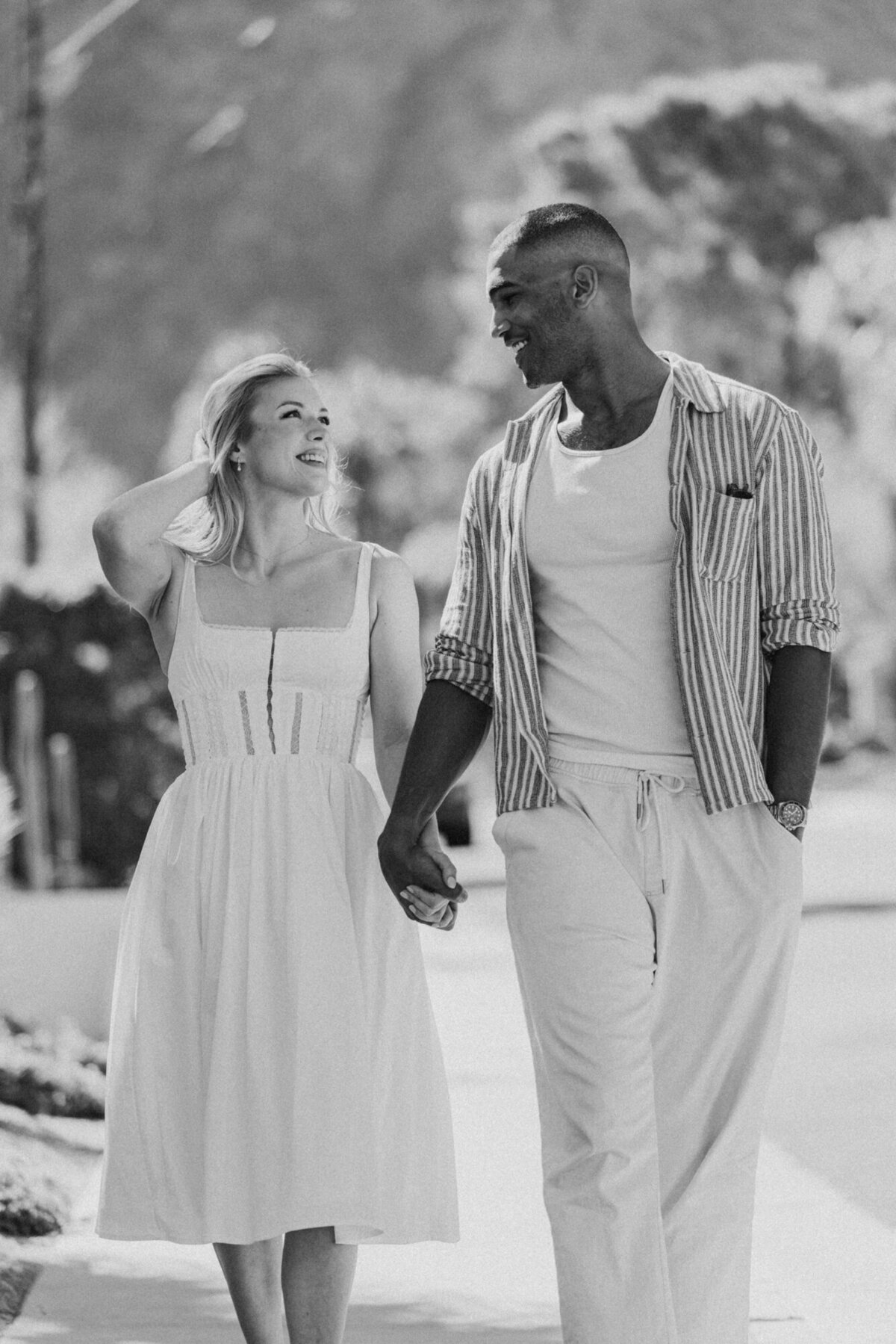 Black and white image of couple dancing outdoors, laughing together during a candid celebration.