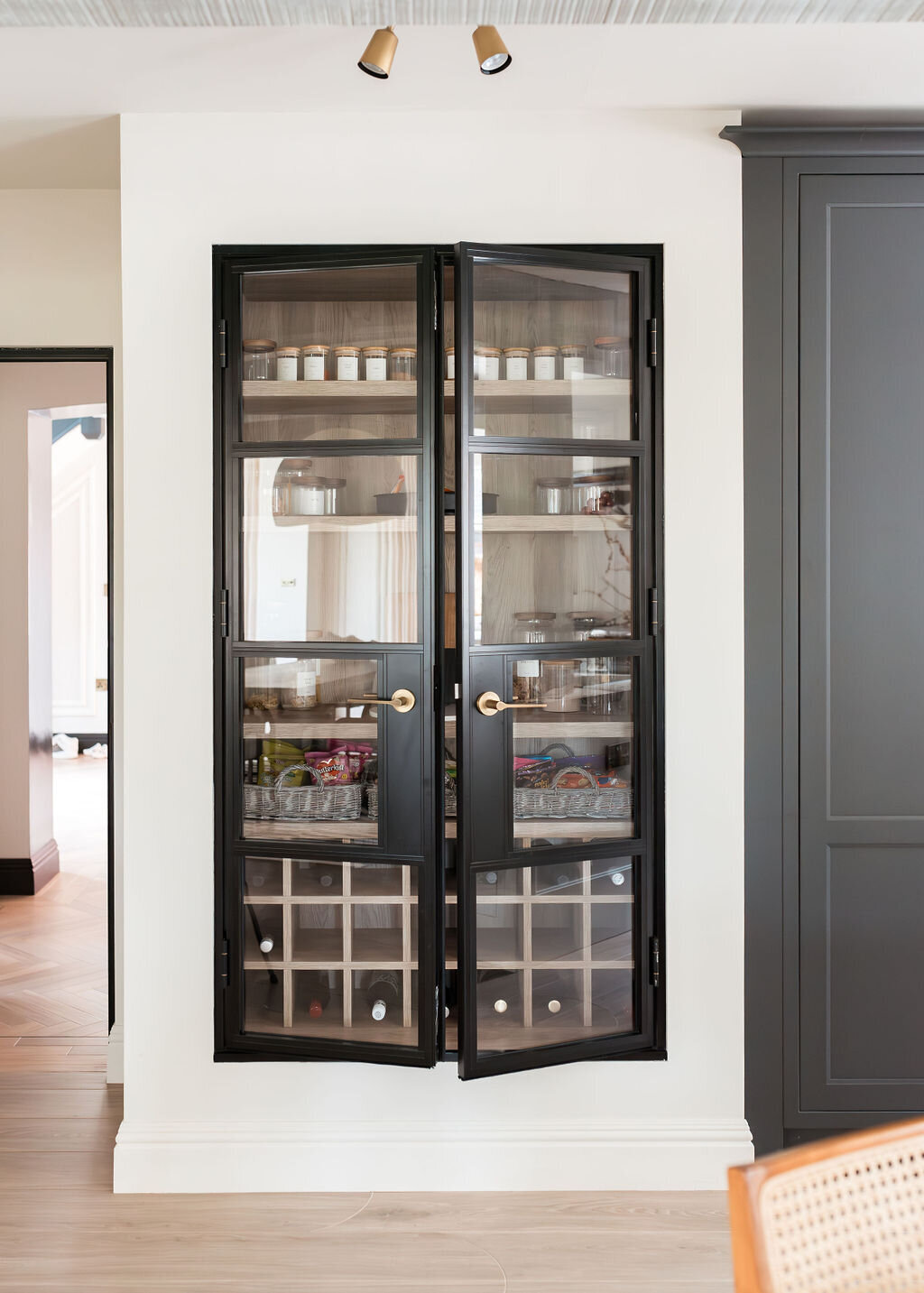 Built-in pantry cabinet with glass doors with black frames.