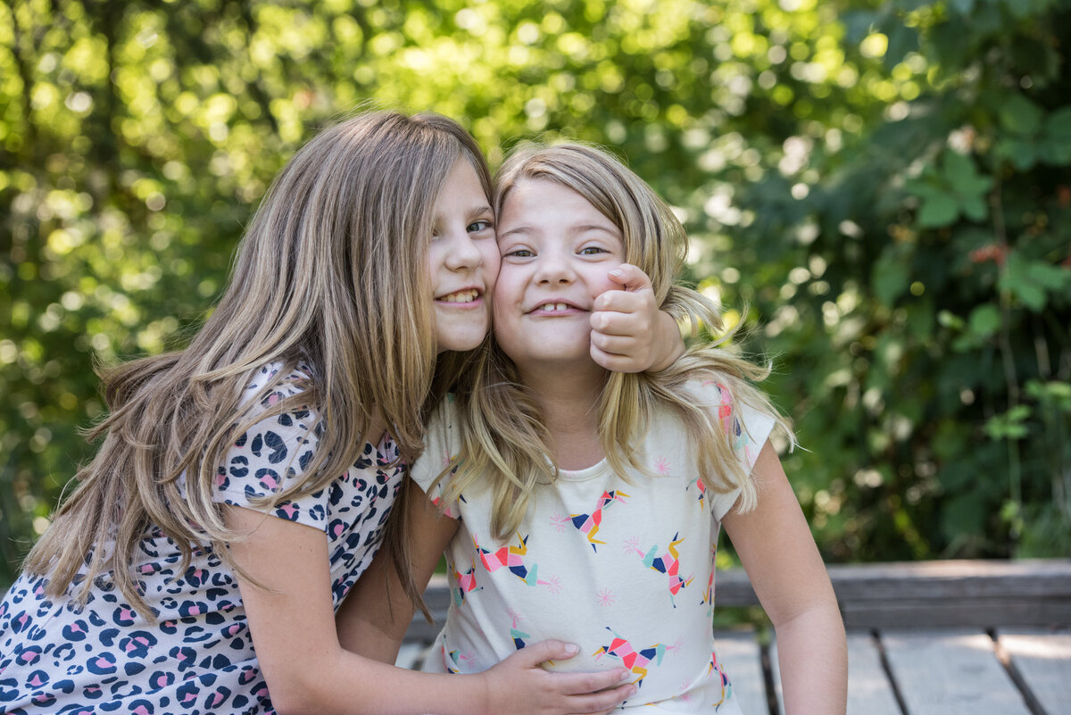 Two kids smiling while one has their arm wrapped around the other.