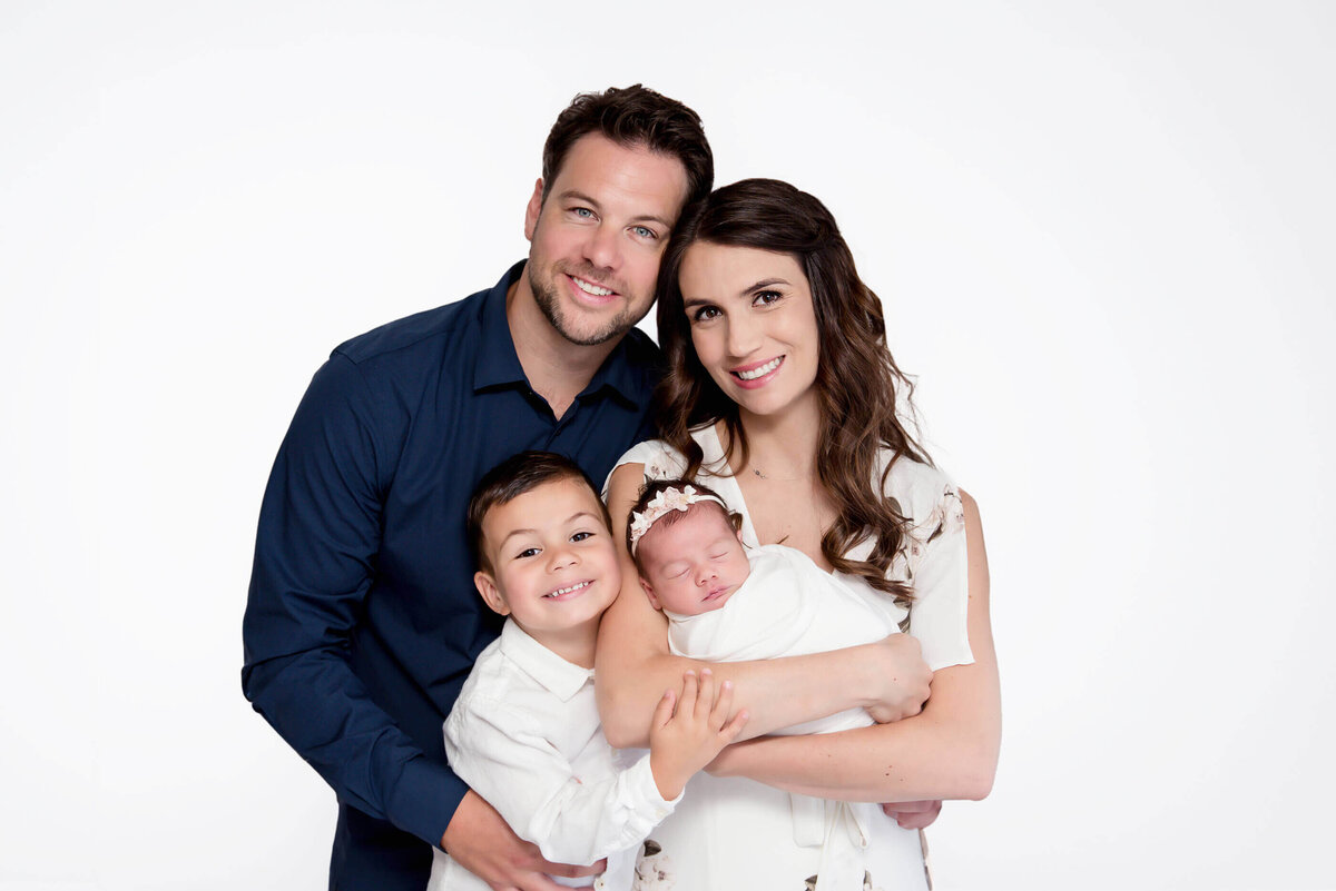 Husband and wife and their son holding newborn baby girl for their family newborn photography session in Burlington, Ontario.