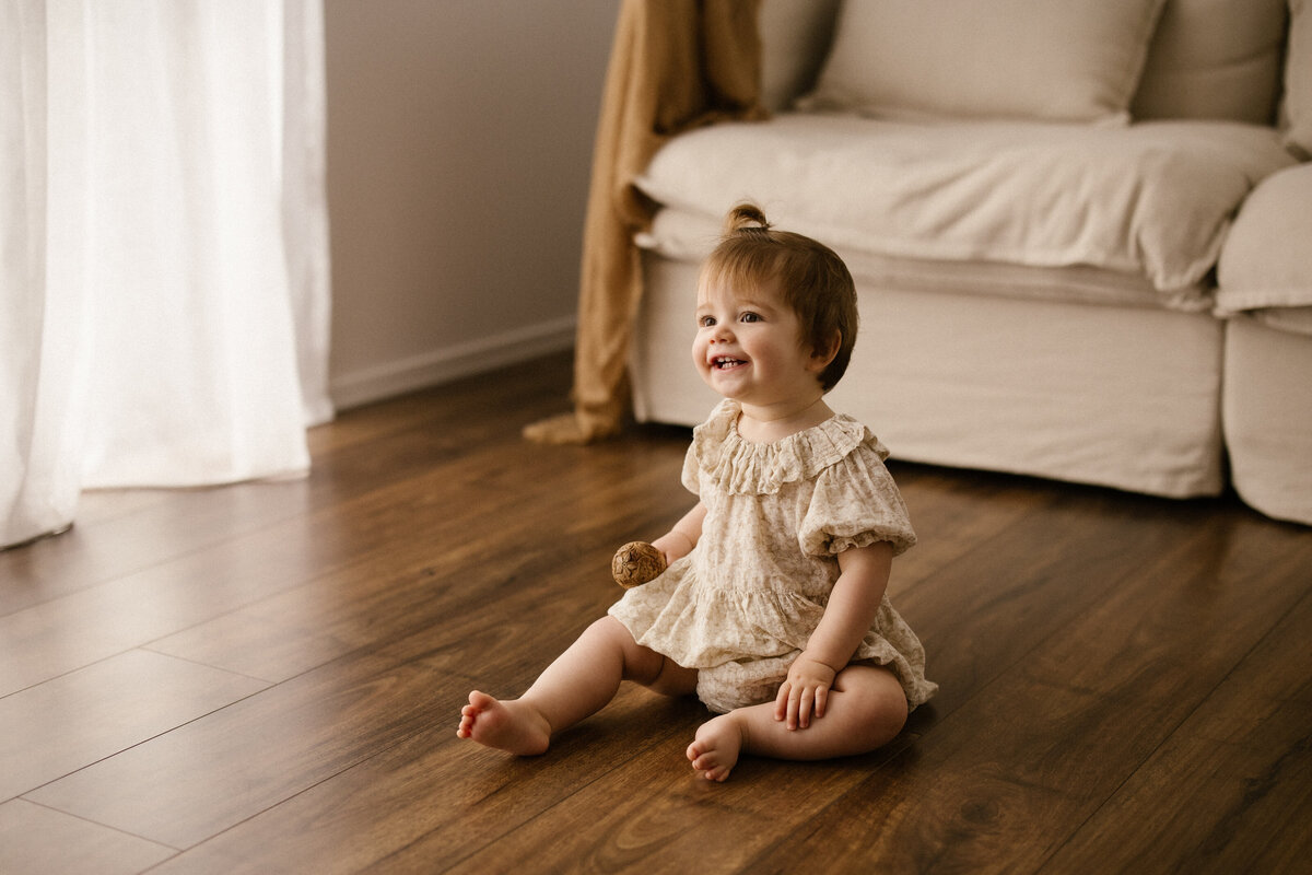 Toddler macie sitting on the studio floor during her first birthday photoshoot in taranaki
