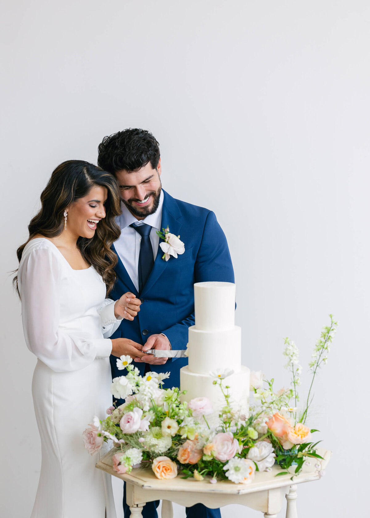 bride and groom cutting into cake surrounded by flowers