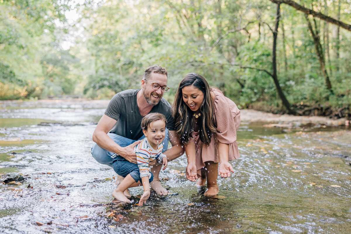 couple playing with toddler son in the creek