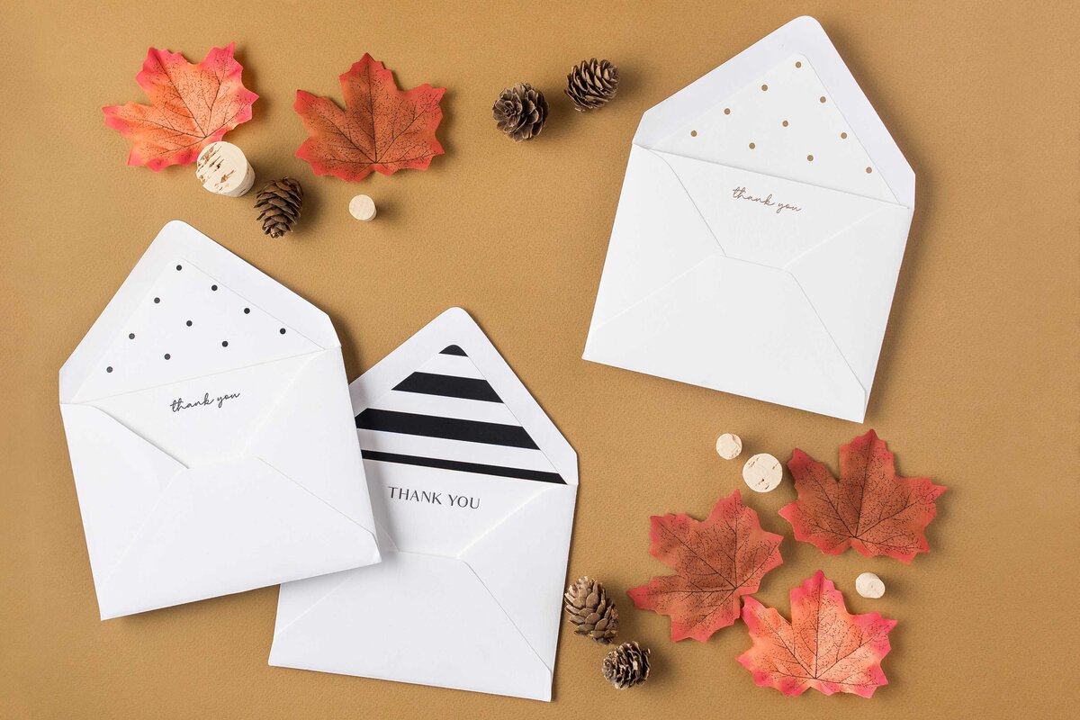 a flat lay of envelopes surrounded by fall leaves