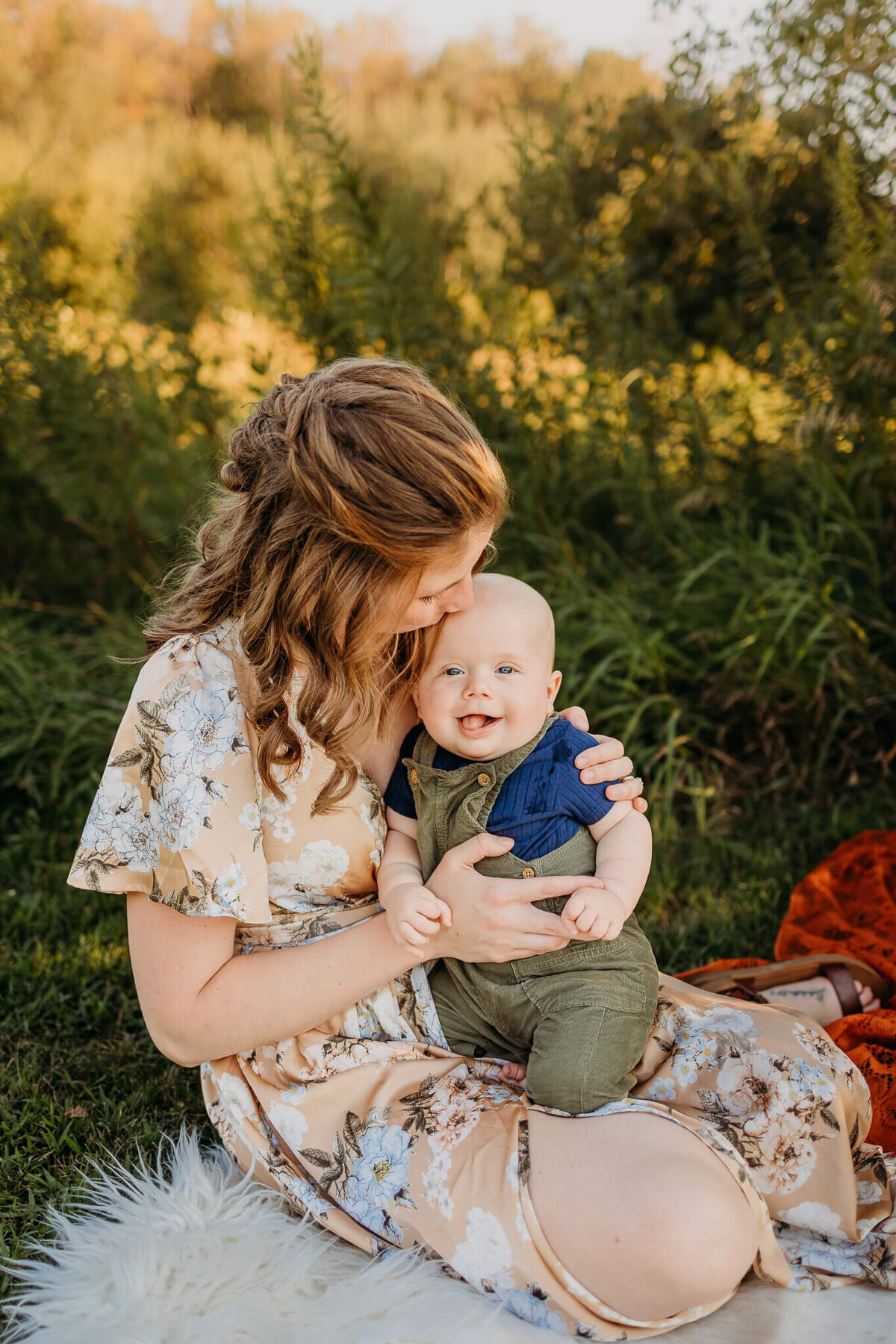 mom in yellow dress holding son outside  on blanket