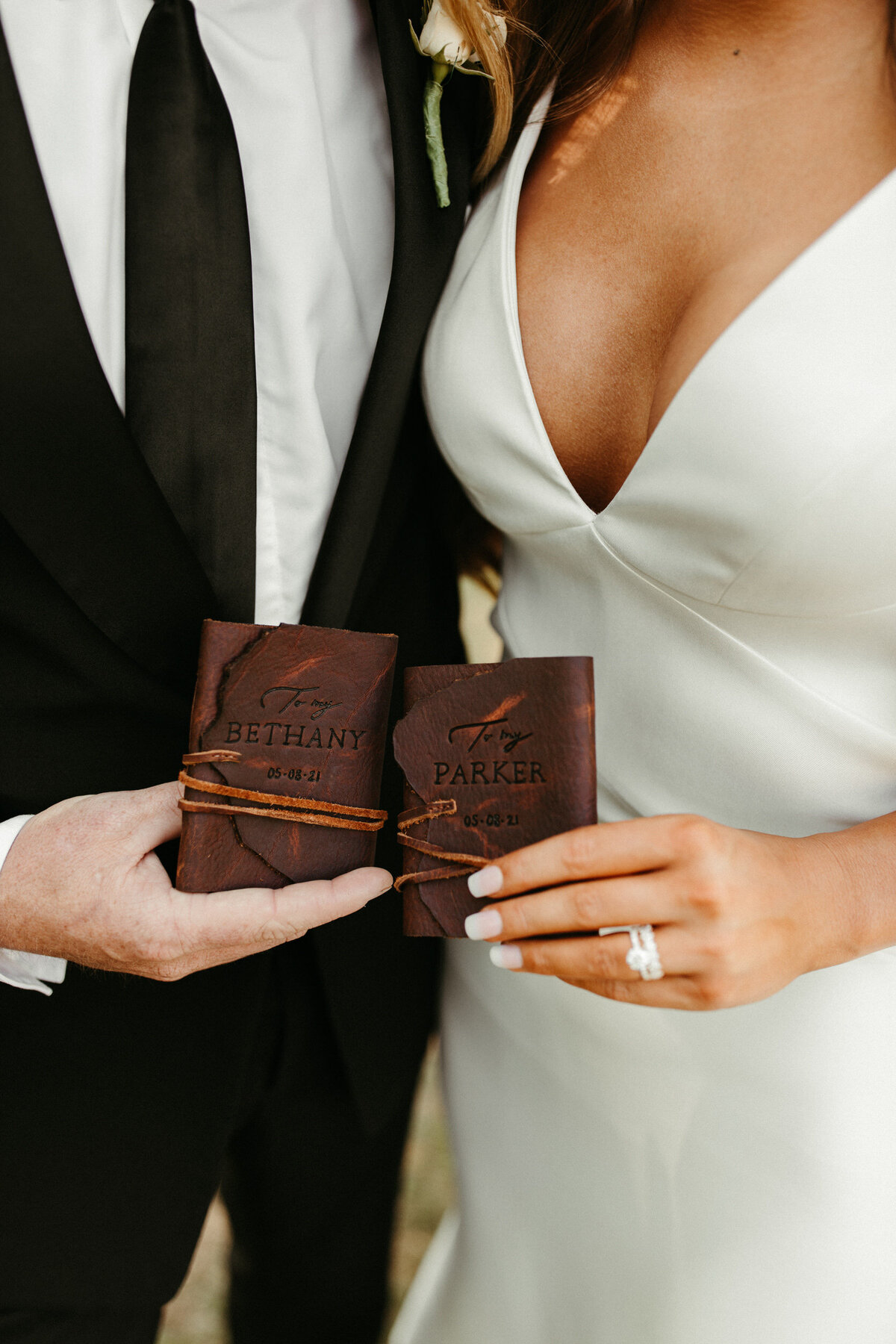 Close up of bride and groom holding their leather vow books with their names engraved into them