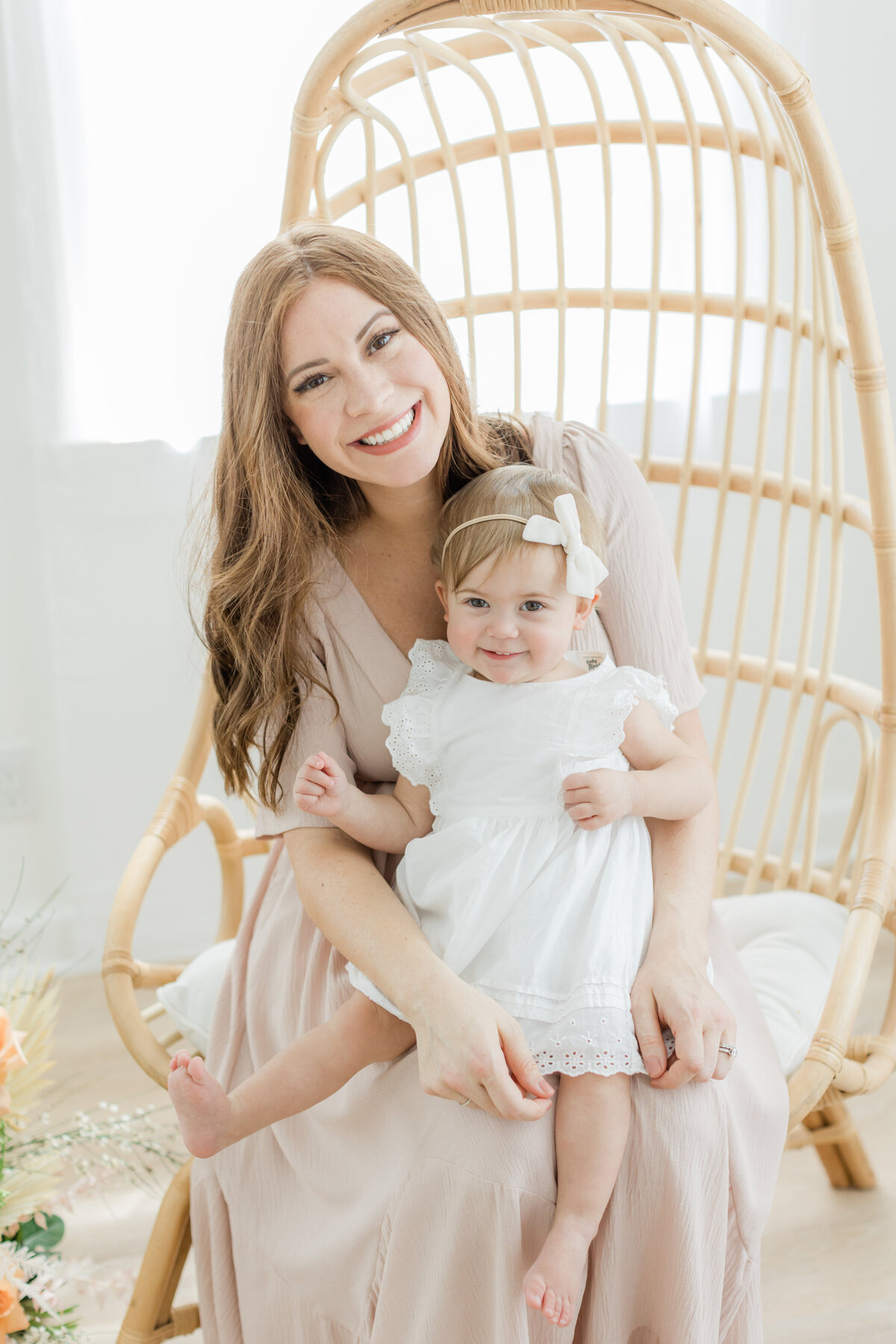 Mom holding her toddler daughter in a rattan chair in Philadelphia Portrait Photographer Tara Federico's studio