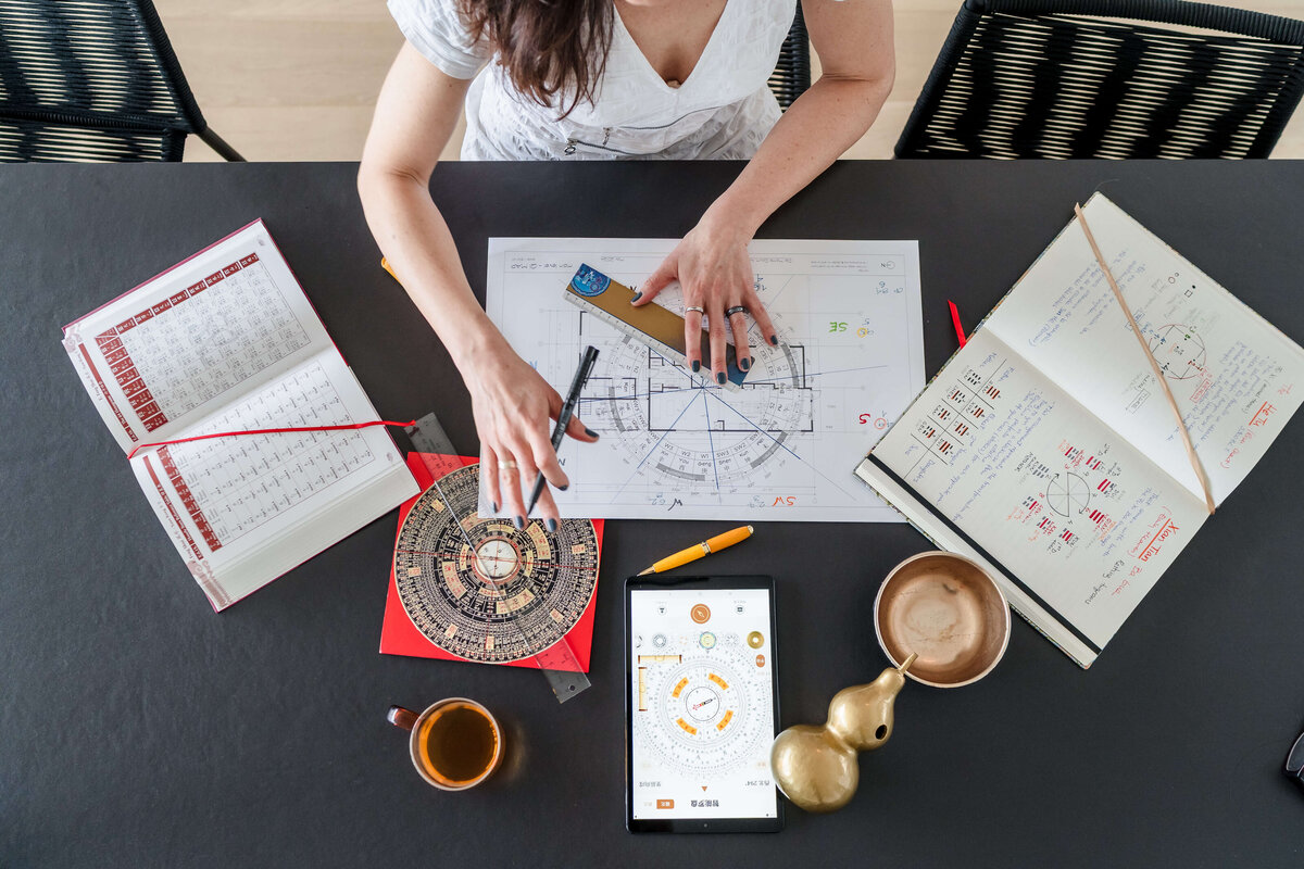 overhead shot of workspace with feng shui charts and woman's hands at work