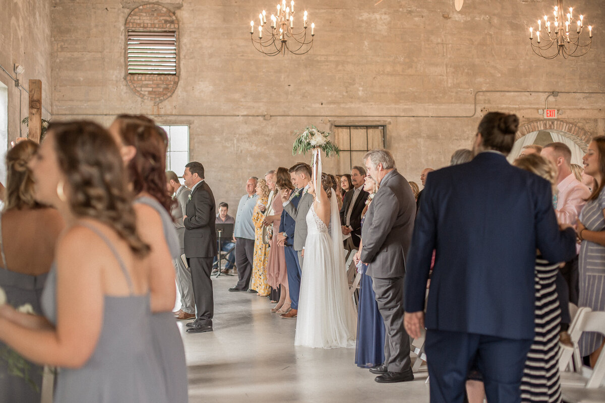 The bride celebrates standing at the alter on her wedding day by raising her bouquet high in the air during the ceremony. Photographed by Stephanie Eddy, Boulder wedding photographer.