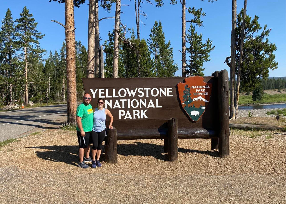 Man and women standing in from of National park sign together