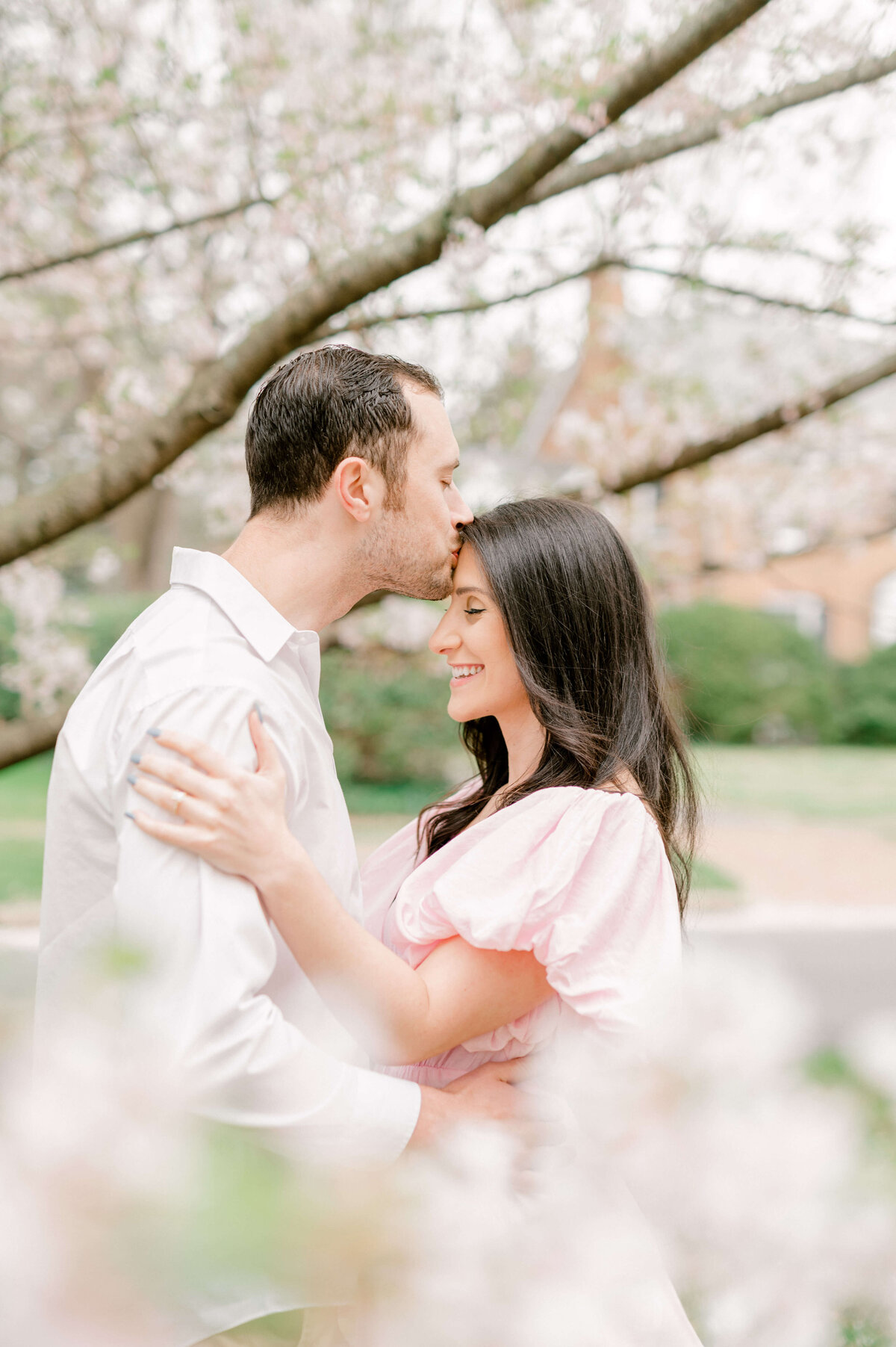 Man kissing fiance's forehead for engagement photos