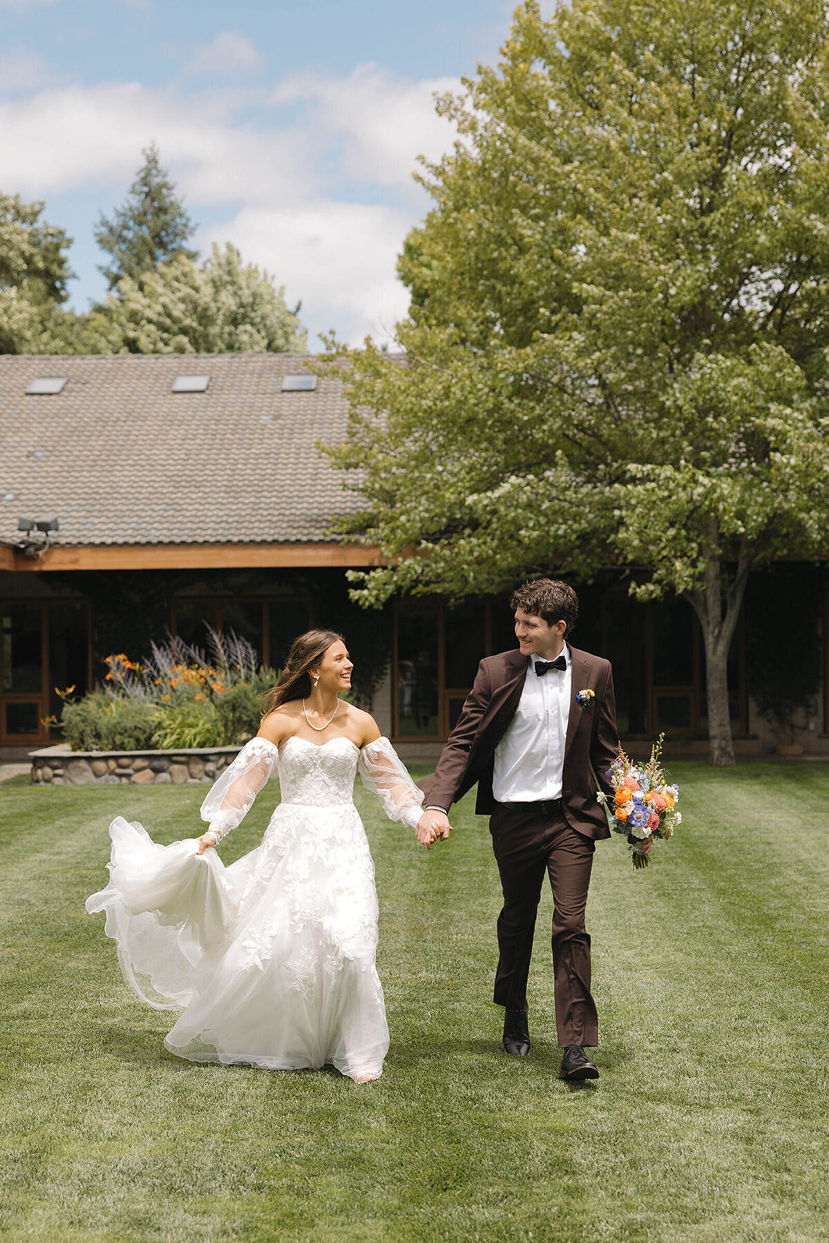 Bride and groom running through the garden laughing