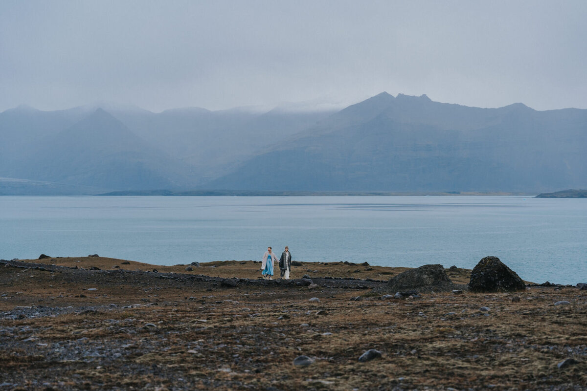 Landscape view of two women walking near the water of an Iceland Beach 
