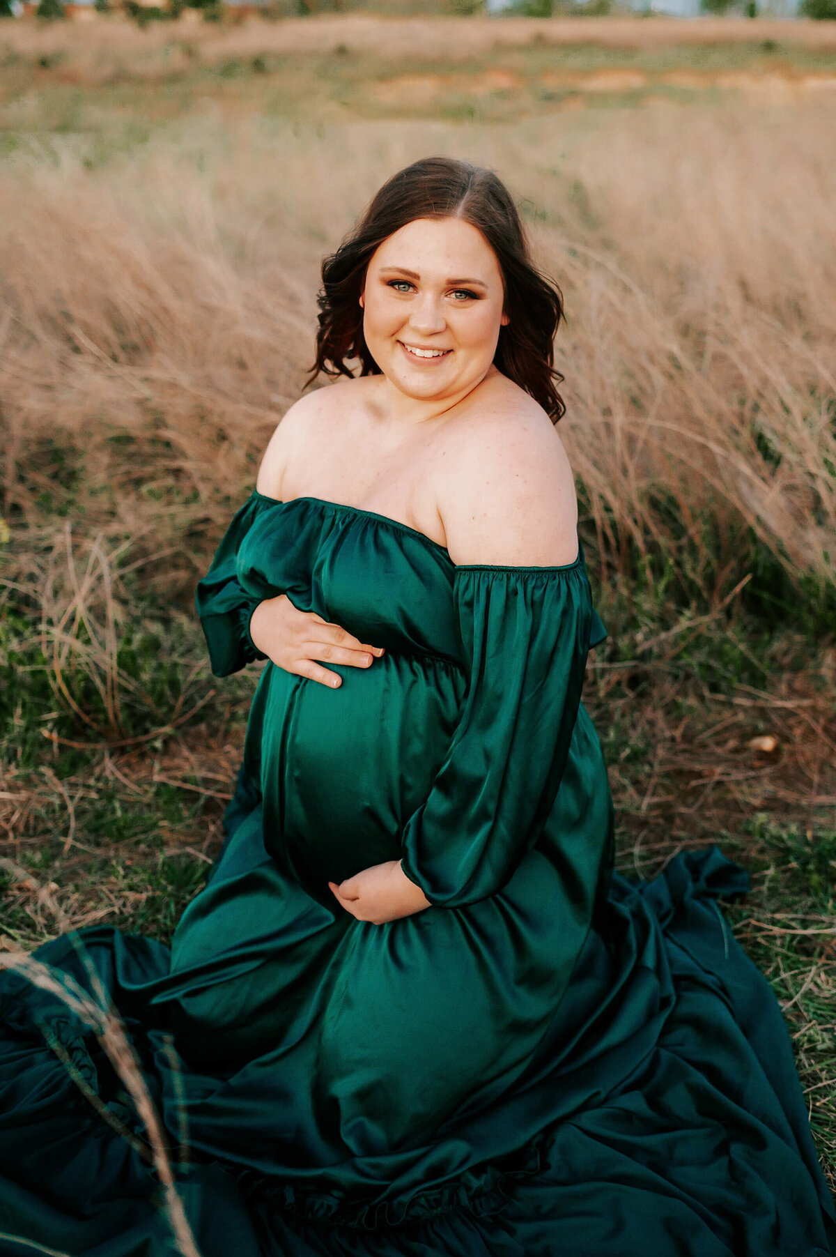 maternity photographer The XO Photography captures pregnant mom kneeling in field in Joplin MO