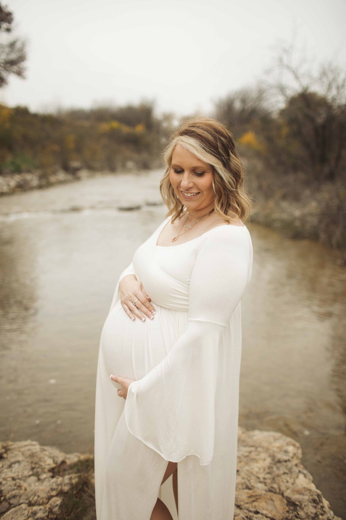A tender maternity photo of the expectant mom in a white maternity dress, holding her daughter close to her while lovingly cradling her belly, captured by Chunky Monkey Photography.