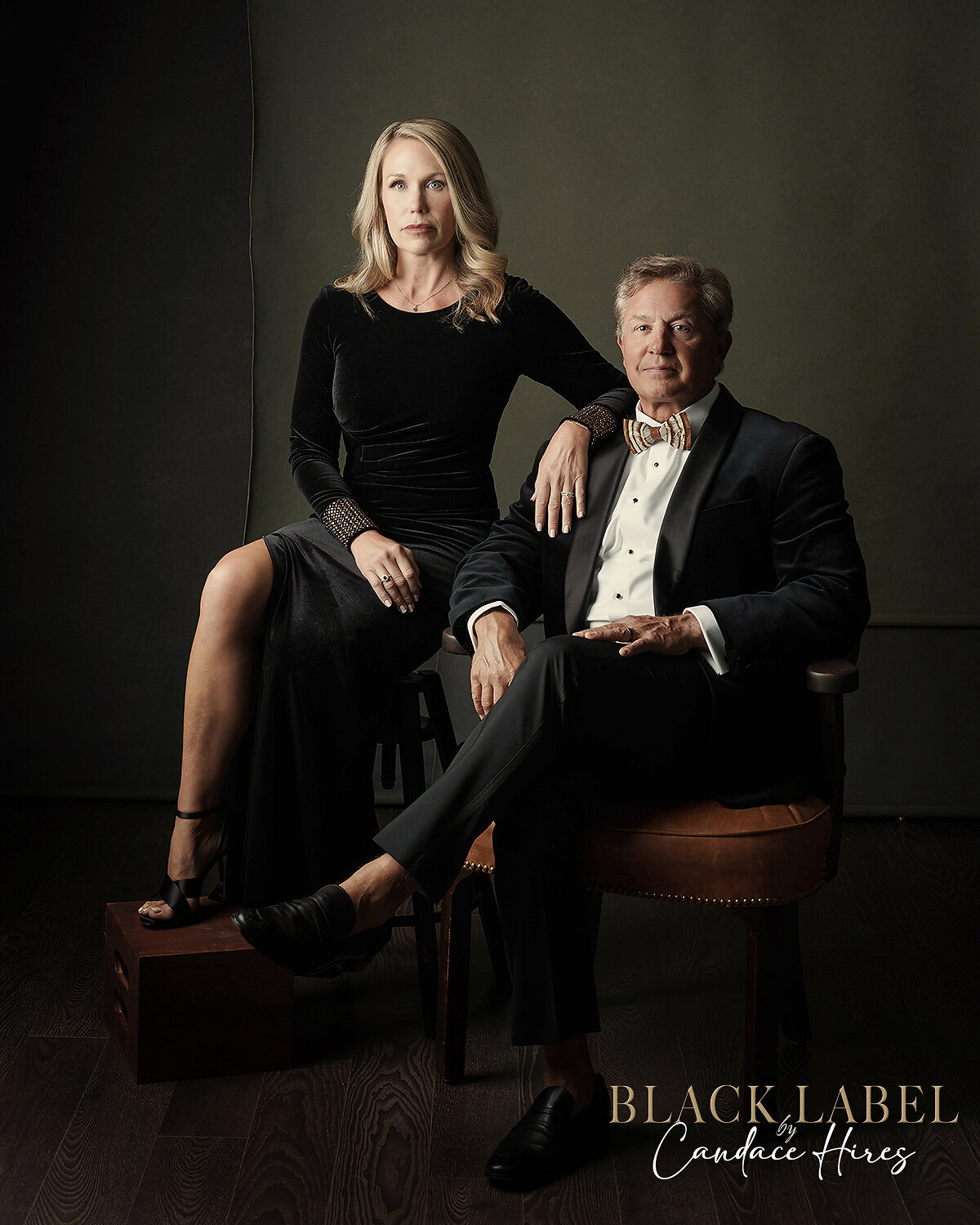 sexy couple in a black gown and black tux photographed in studio in a luxury setting