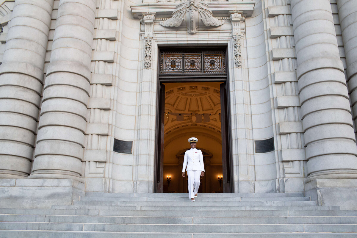 Female Naval officer walks down stairs at Naval Academy.