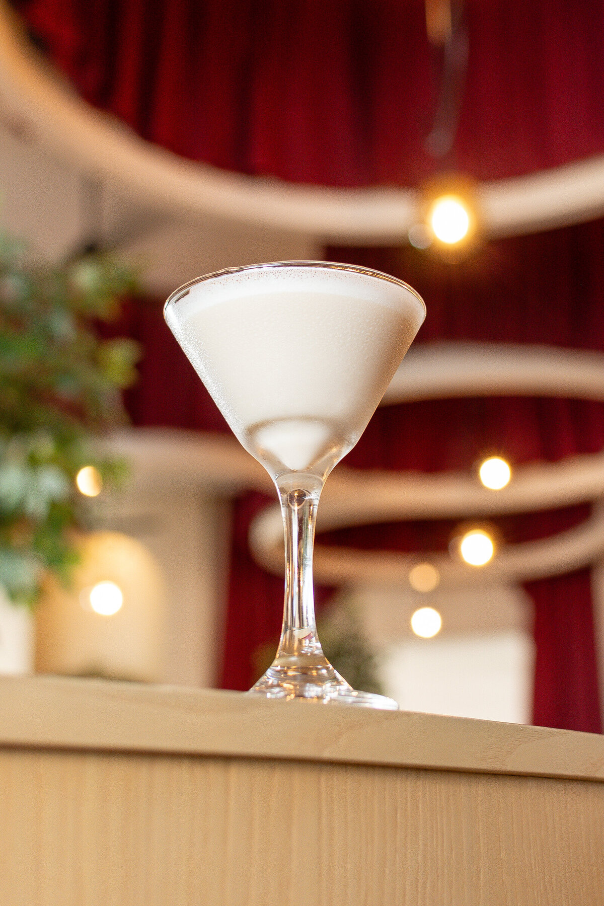 An alexander brandy photographed in a high end bar with red velvet drapes and trees.