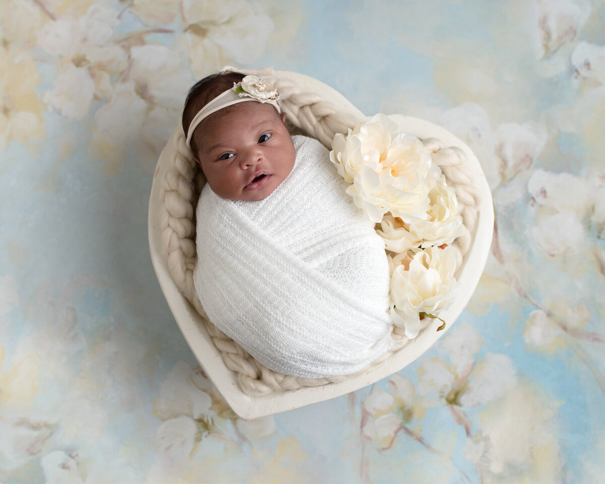 Newborn in a White heart-shaped bucket