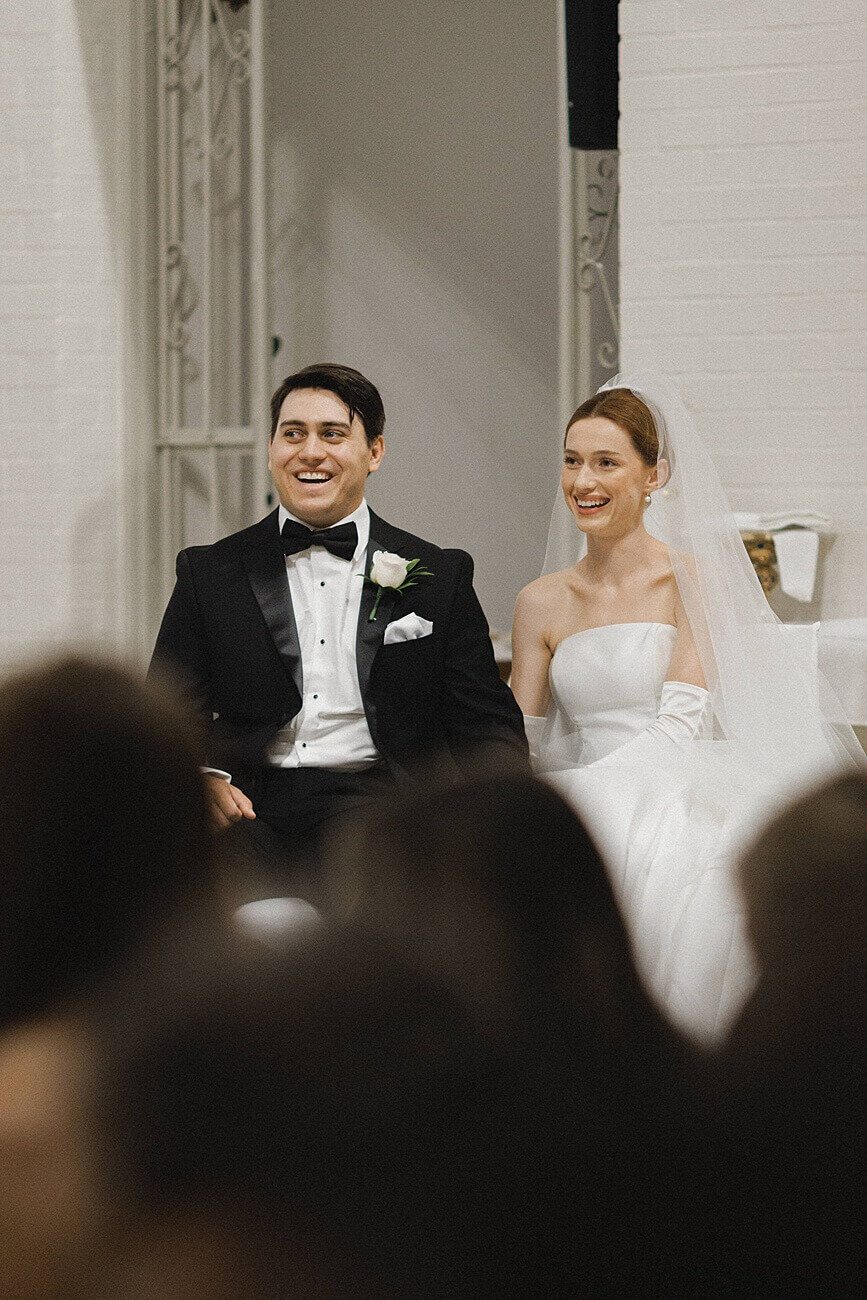 bride and groom laugh while sitting in church