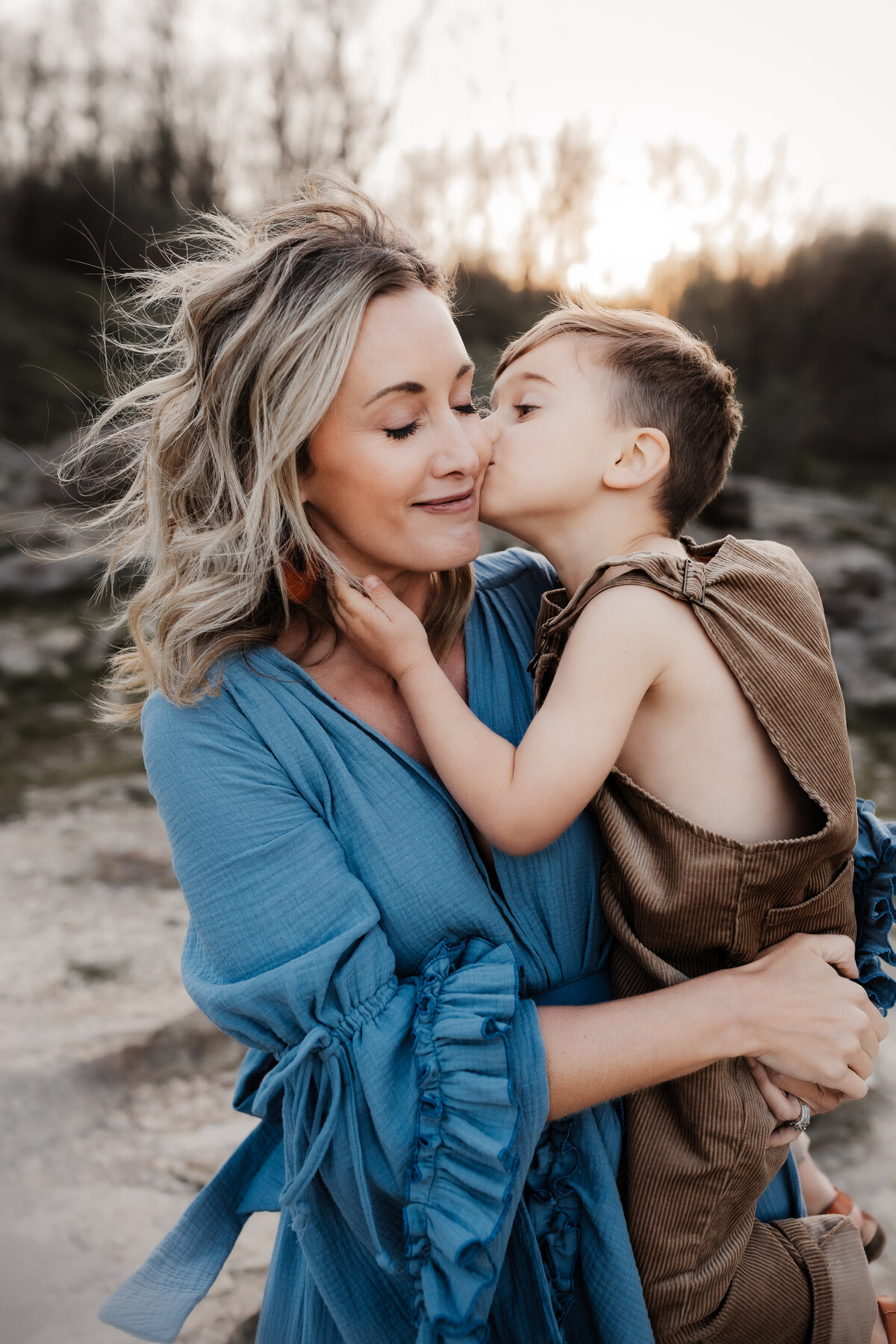 boy in overalls giving cheek kiss to mama