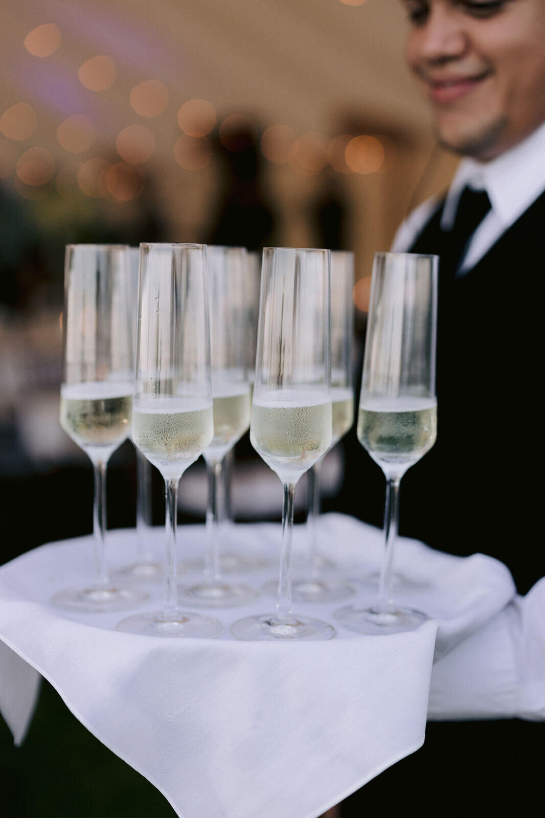 Champagne glasses served by a waiter for a wedding in Cape Cod Summer Tent, MA