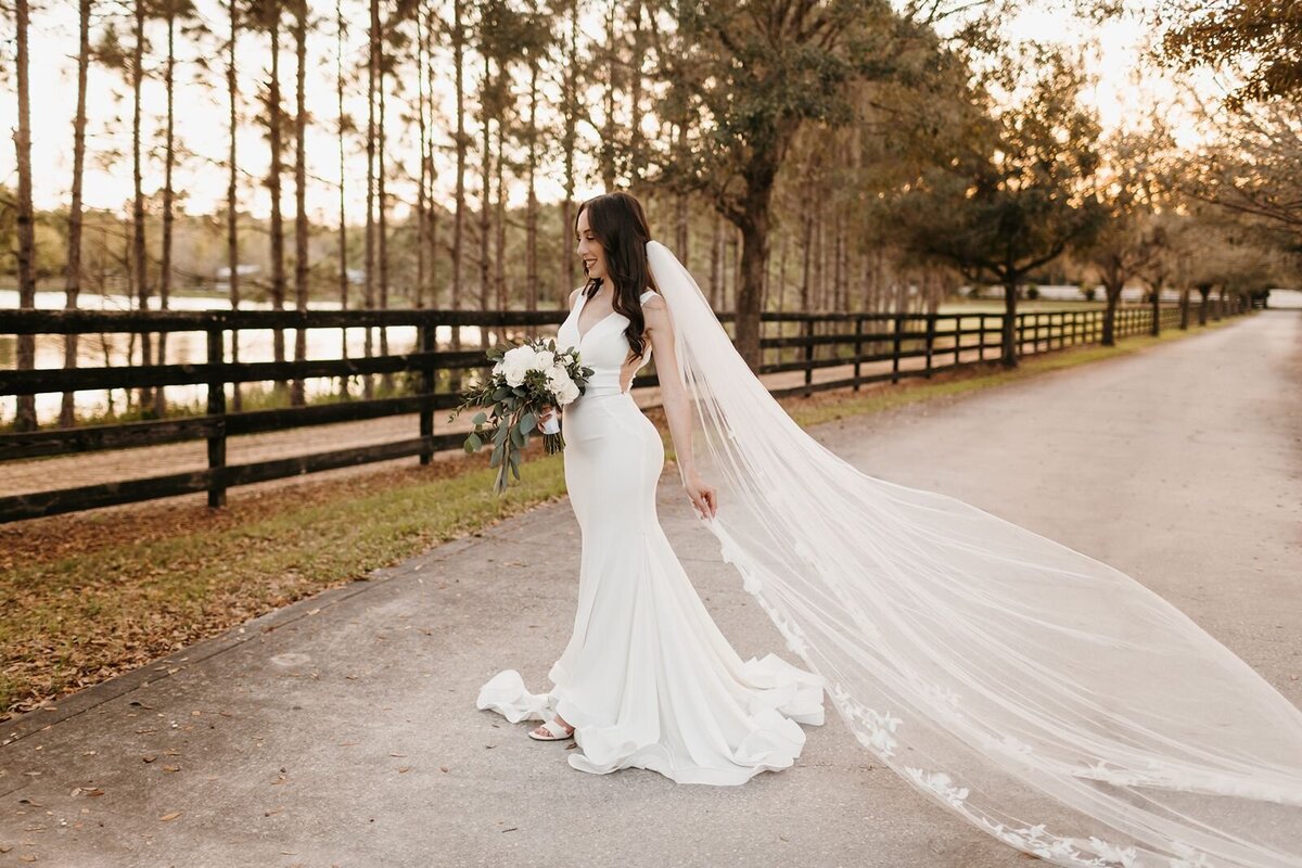 Bride with long veil by lake at Club Lake Plantation in Apopka, Fl