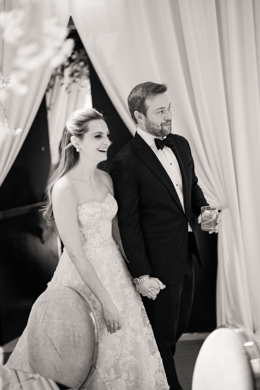 Black and white photo of the bride walking with the groom. 