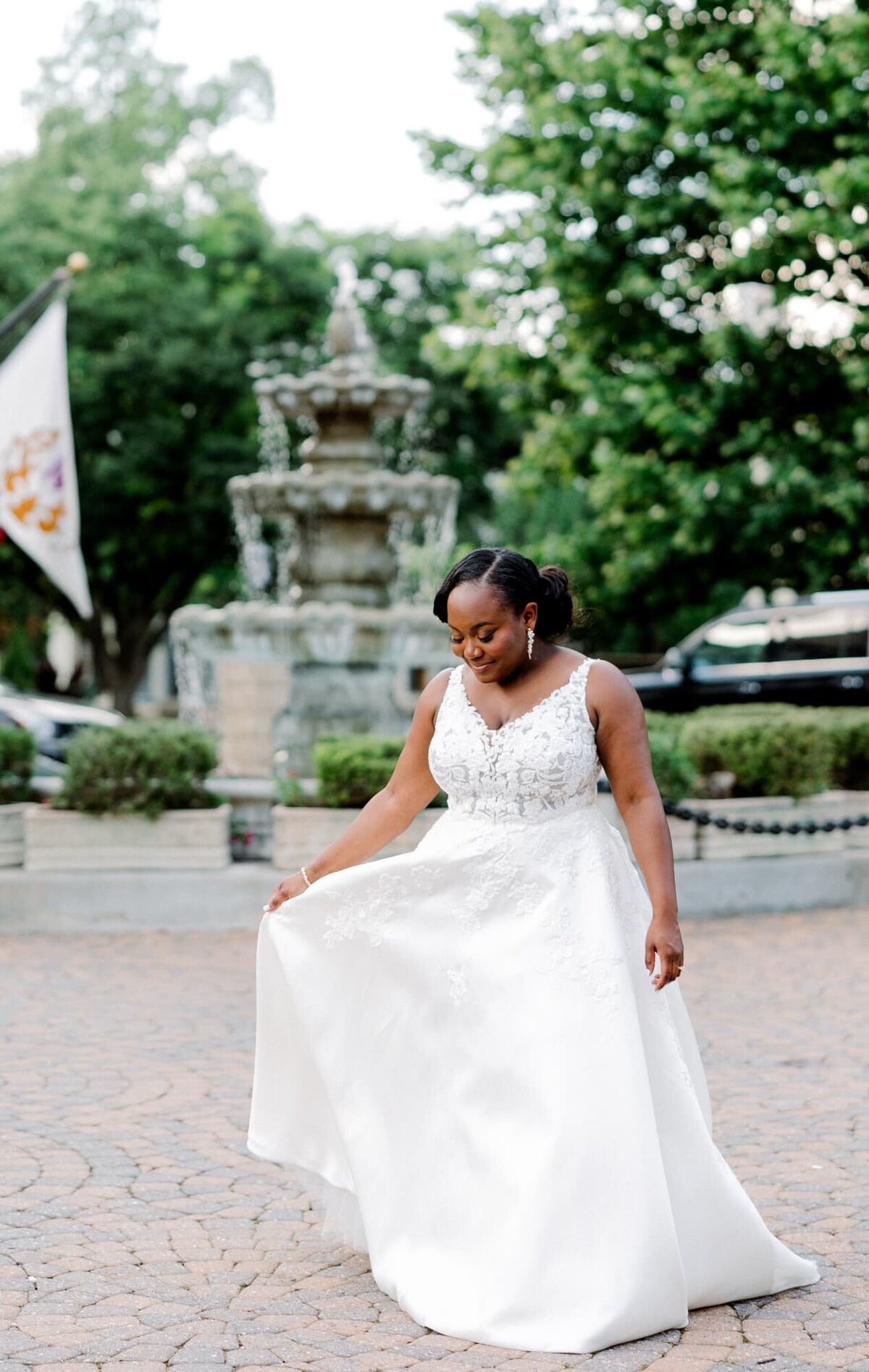 Bride looks down at her dress in front of fountain at Jefferson Hotel Richmond wedding