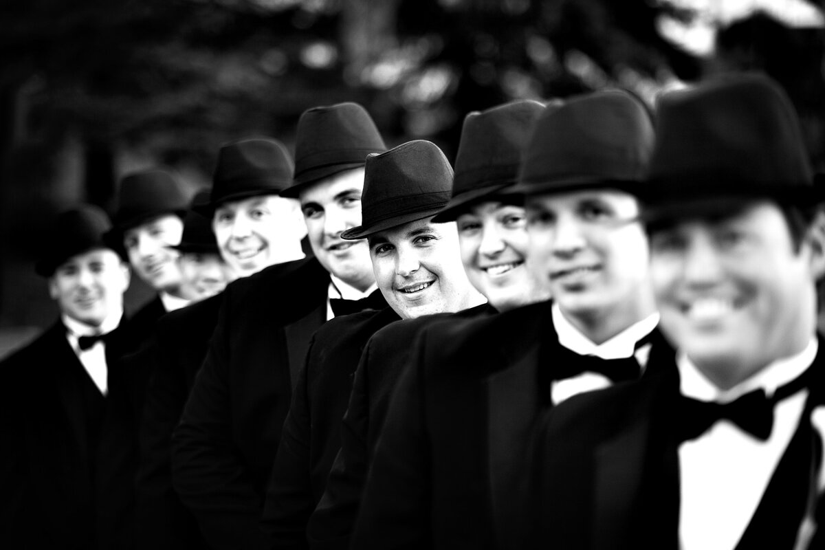 A creative photo of the groomsmen wearing fedora hats and black bow ties.