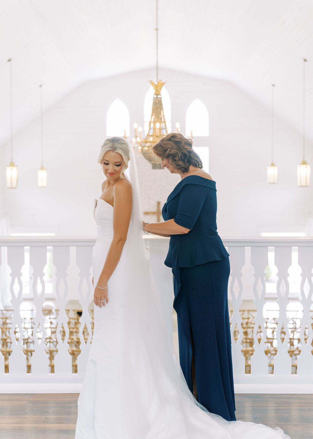 a mom helping her daughter zip up her wedding dress