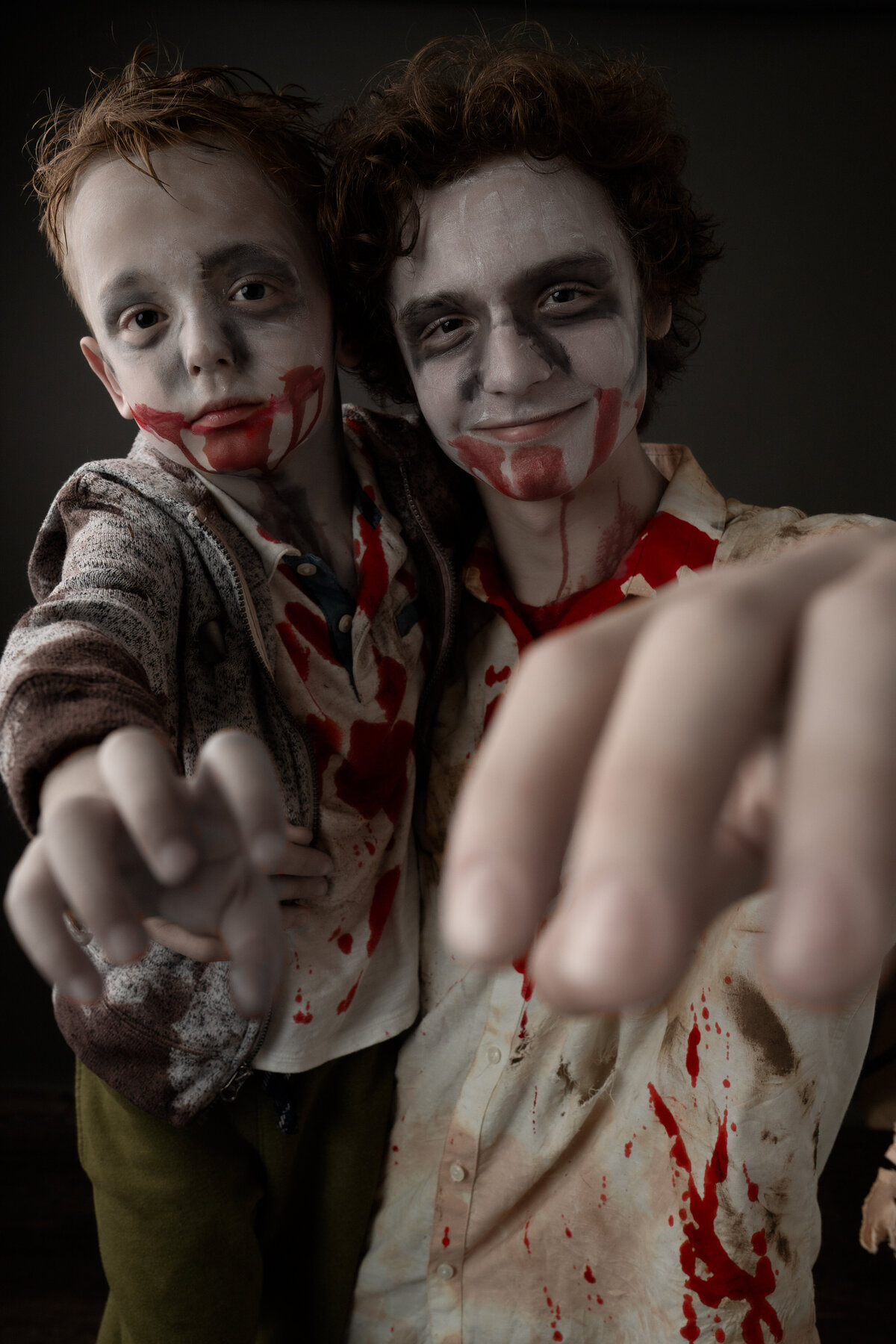 Two brothers dressed as zombies with their arms raised towards camera for Halloween Studio portraits taken in Holly Springs, NC.