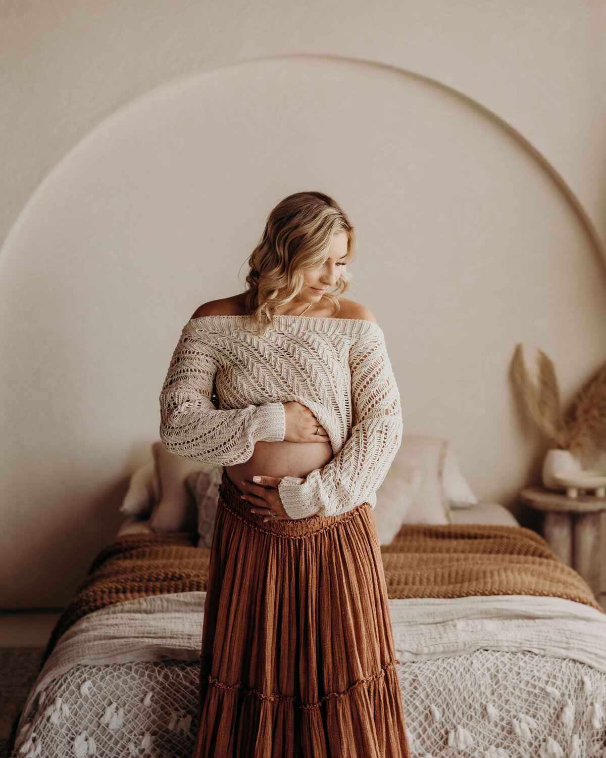 young pregnant mom rubs pregnant belly in boho skirt