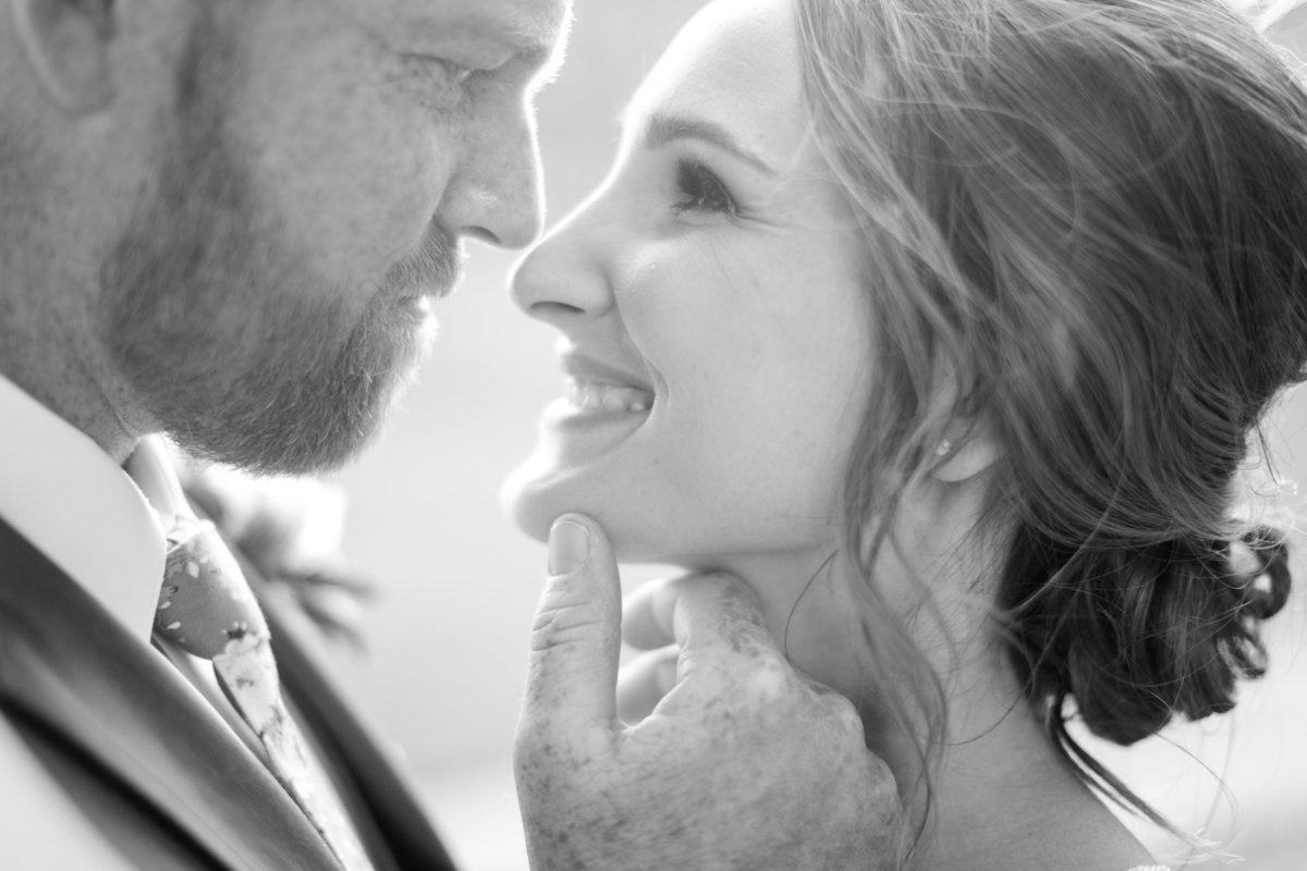 Close up on just married couple with groom gingerly holding his bride's chin in his hand