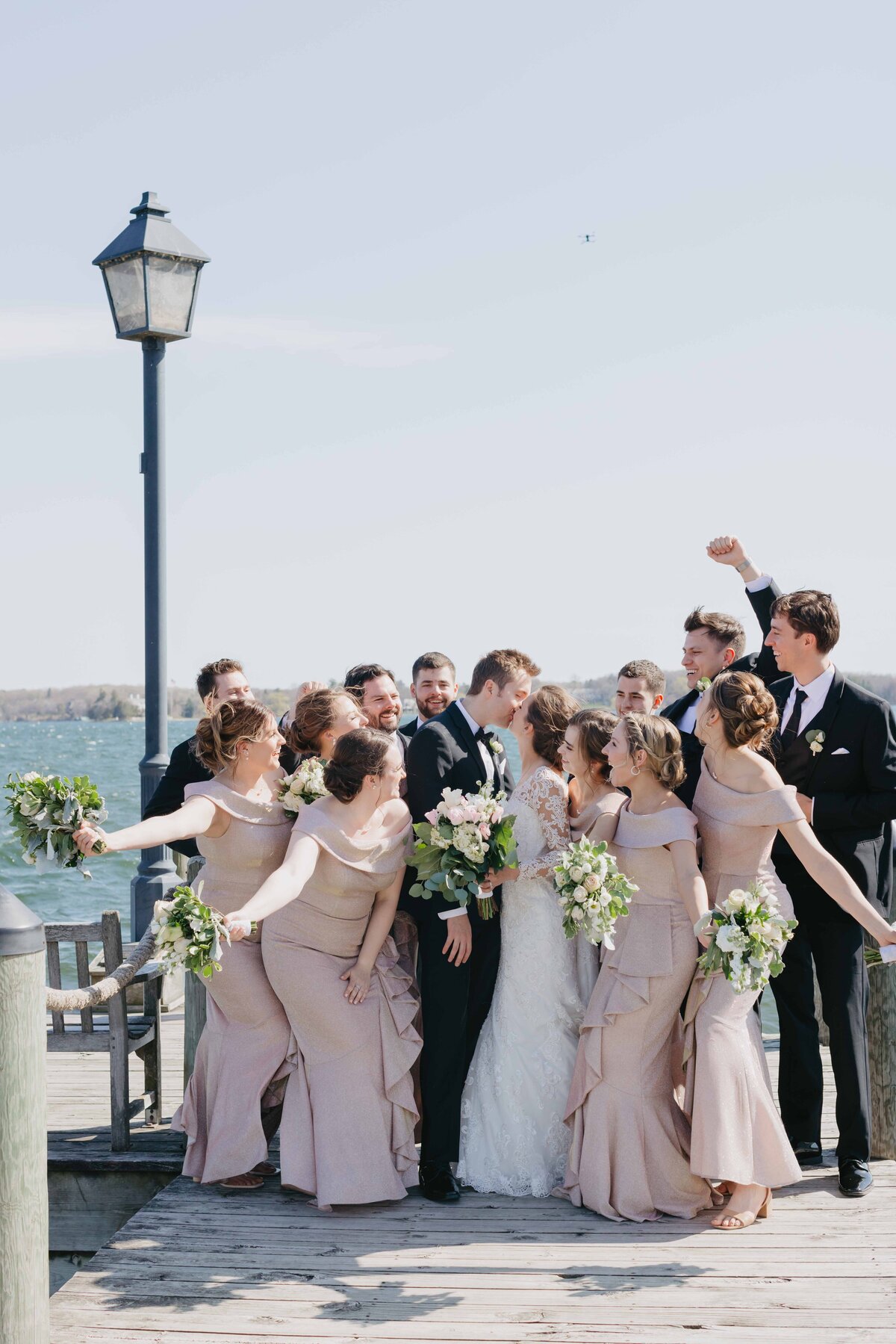 wedding party surround kissing couple on the Wayzta dock