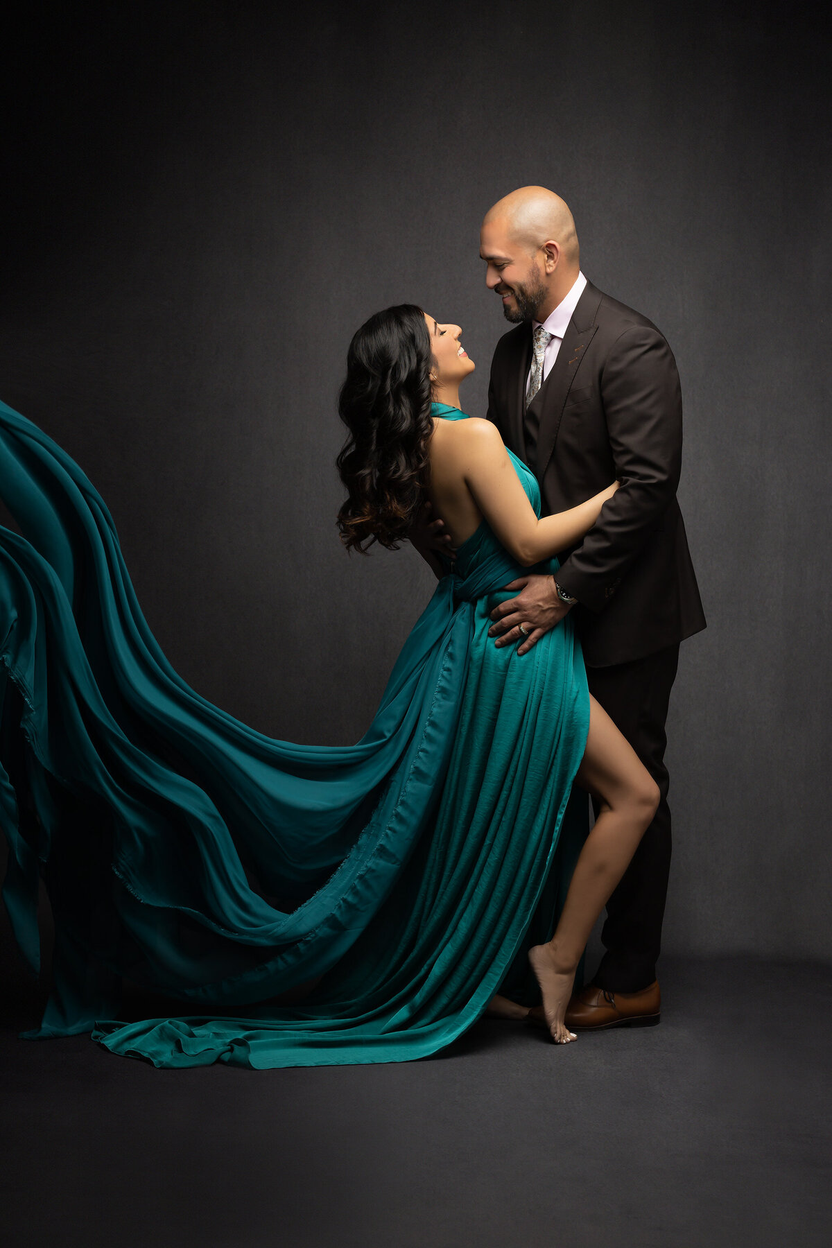 Family photographer in Texas captures a romantic moment between a couple in teal flowing dress and brown suit.