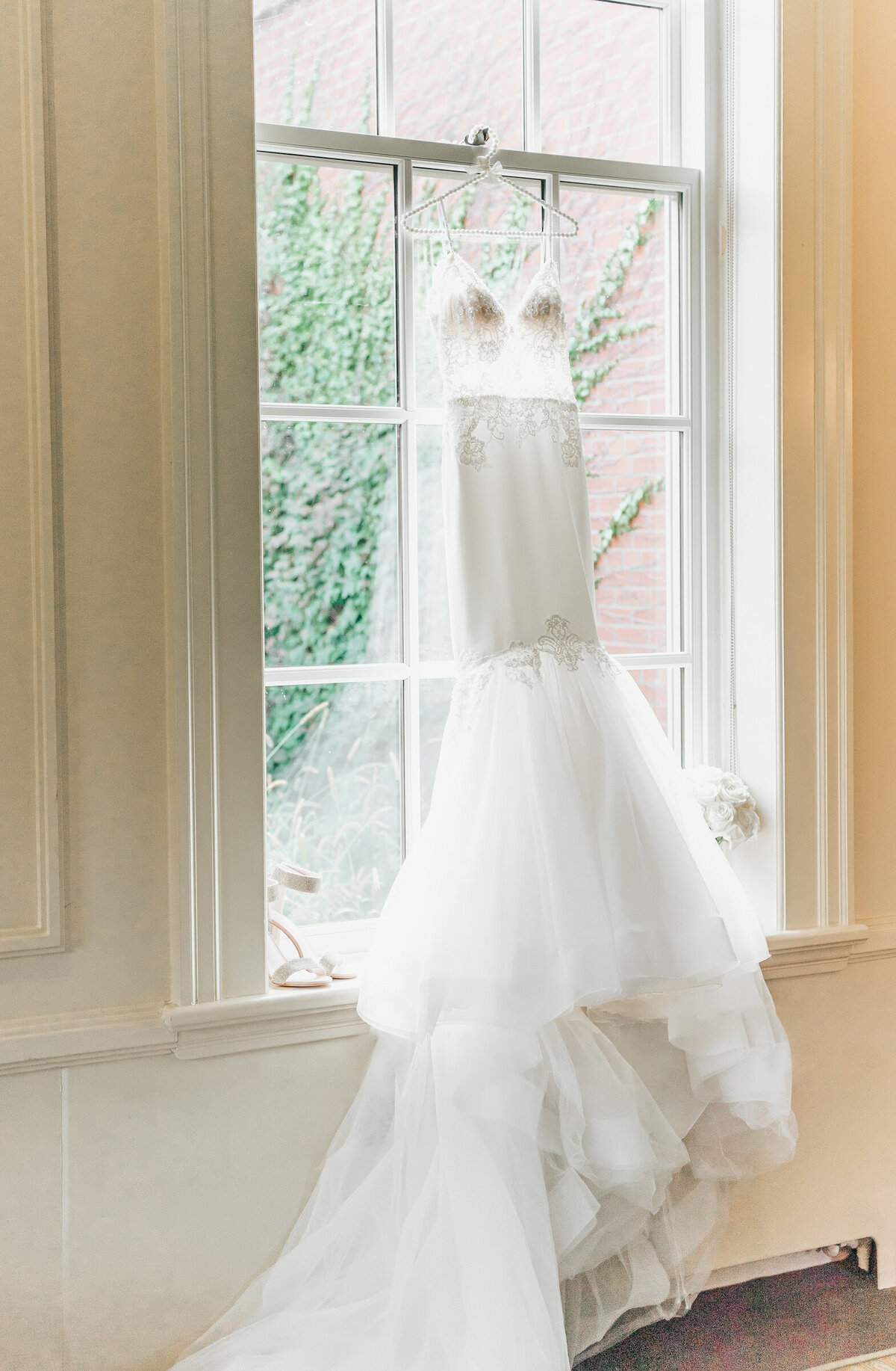 Elegant wedding dress hanging in a window on a wedding day