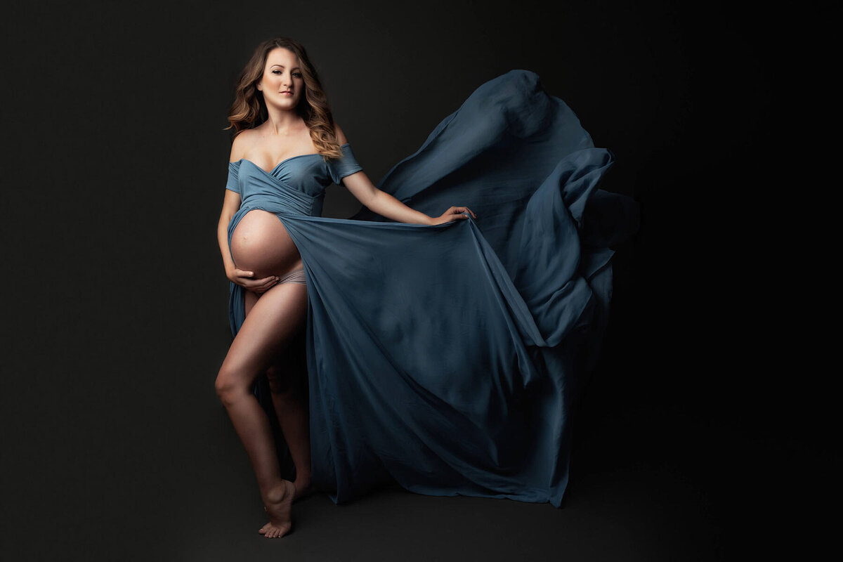 Stunning maternity portrait of a woman in a flowing blue dress