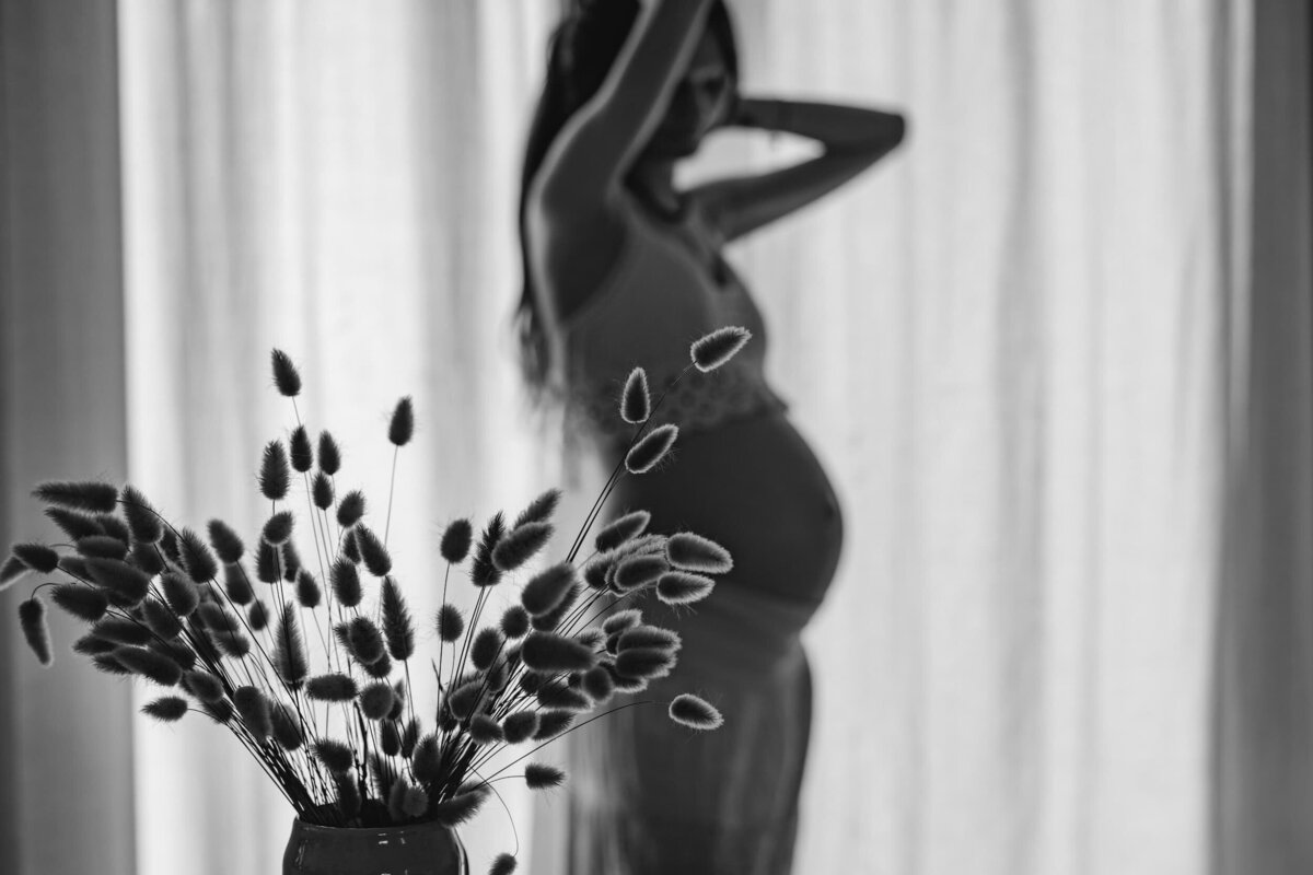 photo de grossesse en noir et blanc à contre jour avec un premier plan sur un bouquet