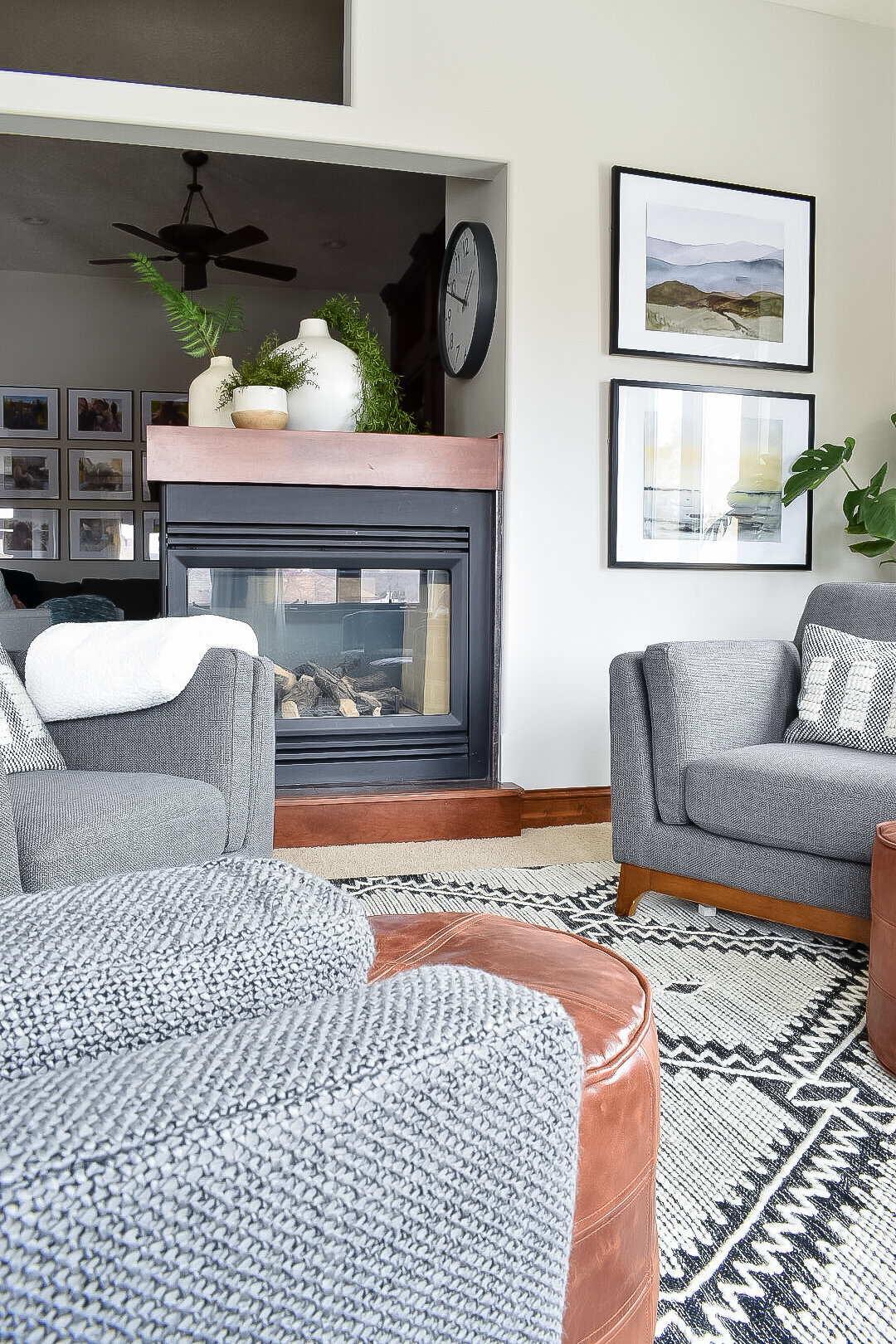 A black fireplace with a wooden mantel separates a seating area from a dining room