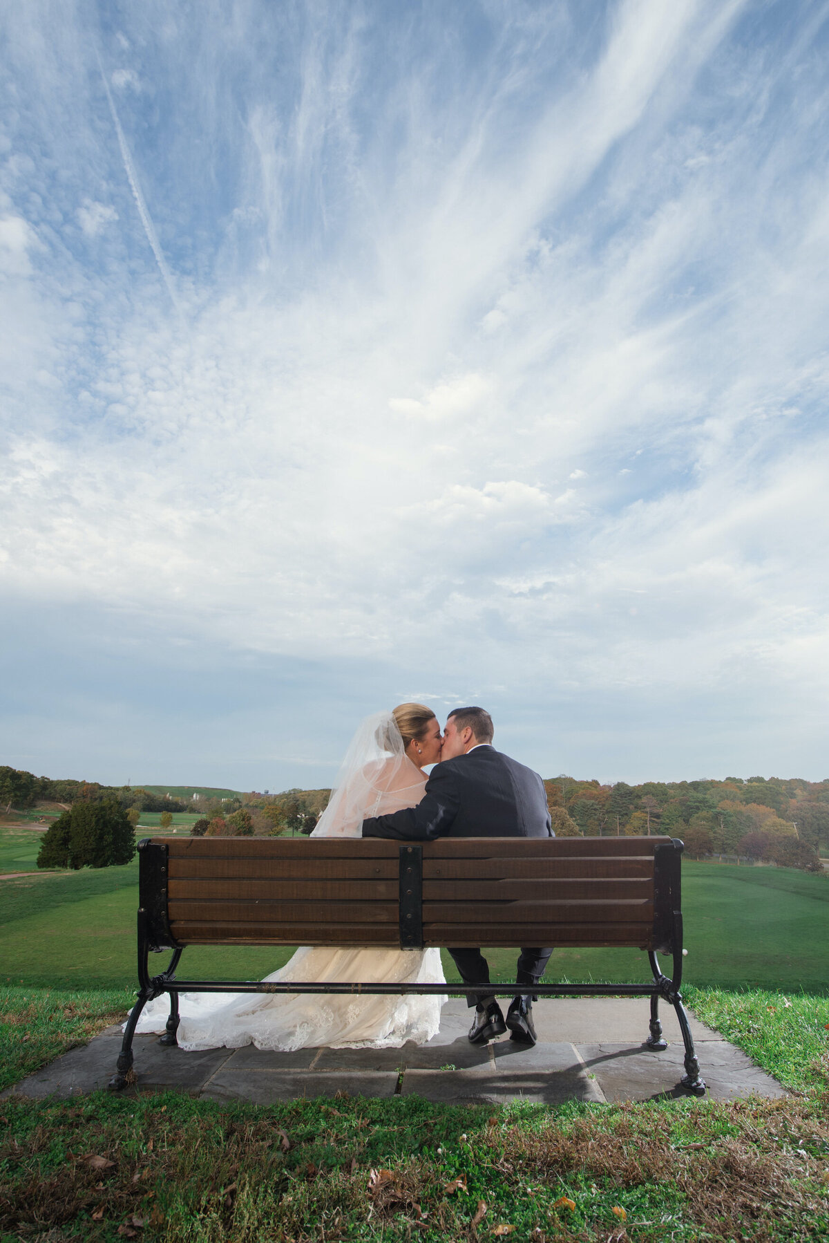 bride and groom kissing on the bench at Heritage Club at Bethpage