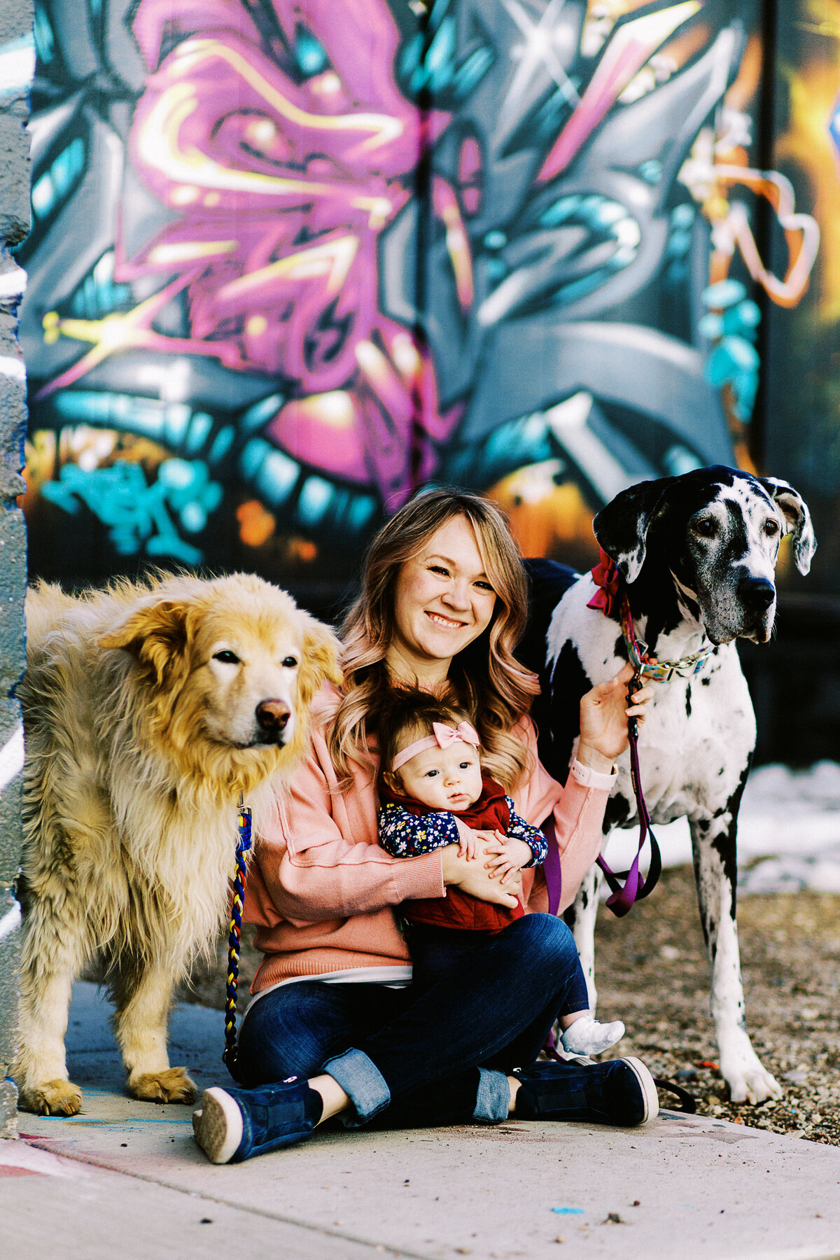 a mom and her baby pose with dogs in front of a colorful all in rino
