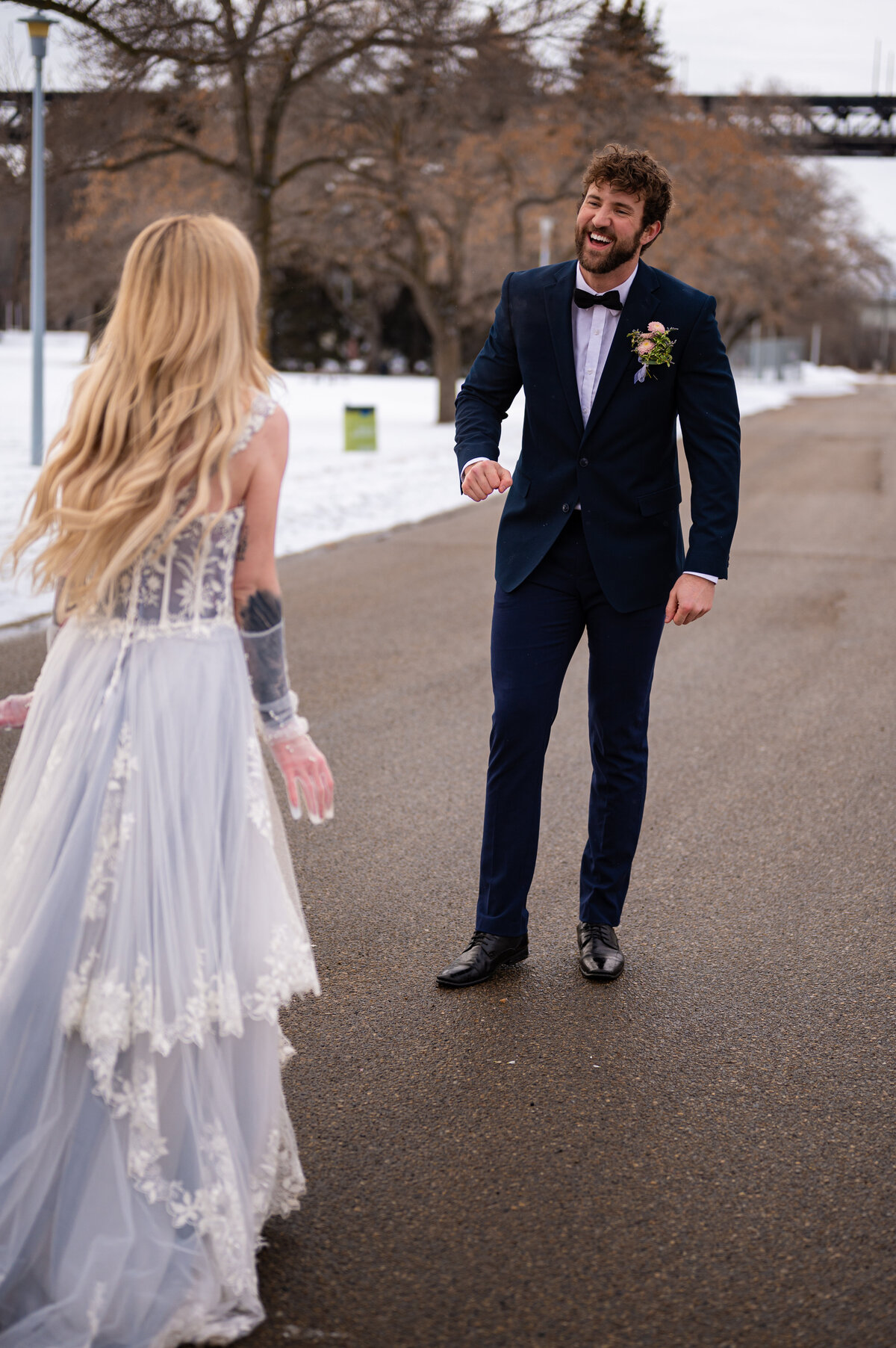bride running into her grooms arms on a snowy path in Edmonton, Alberta