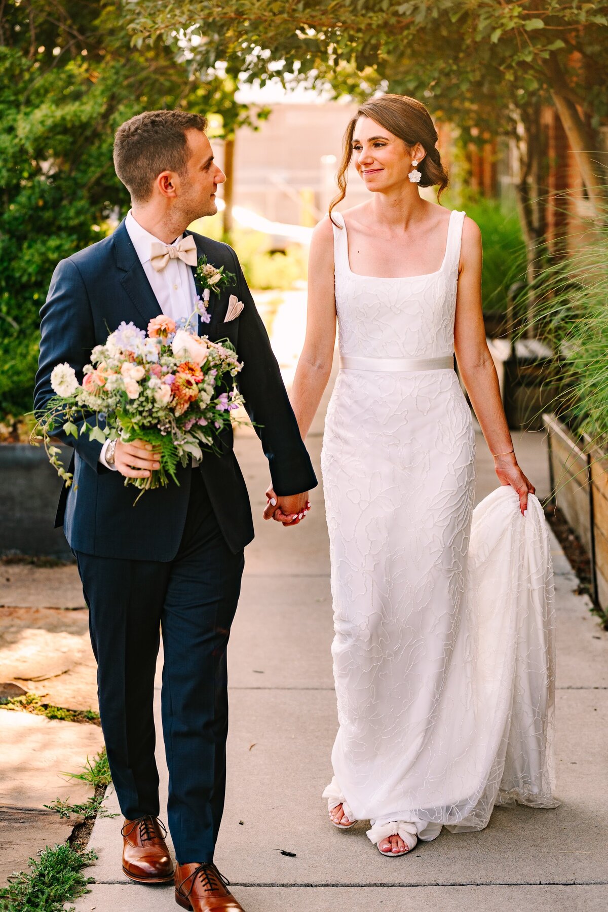 Bride and groom hold hands on their wedding day in downtown Denver.