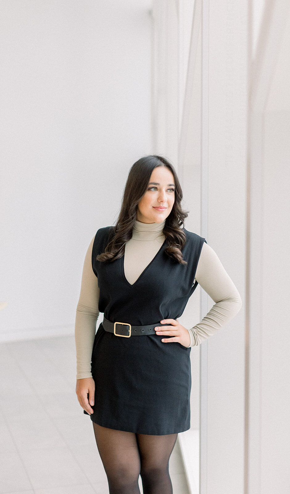 Confident Calgary business woman with hand on hip in a bright and airy room